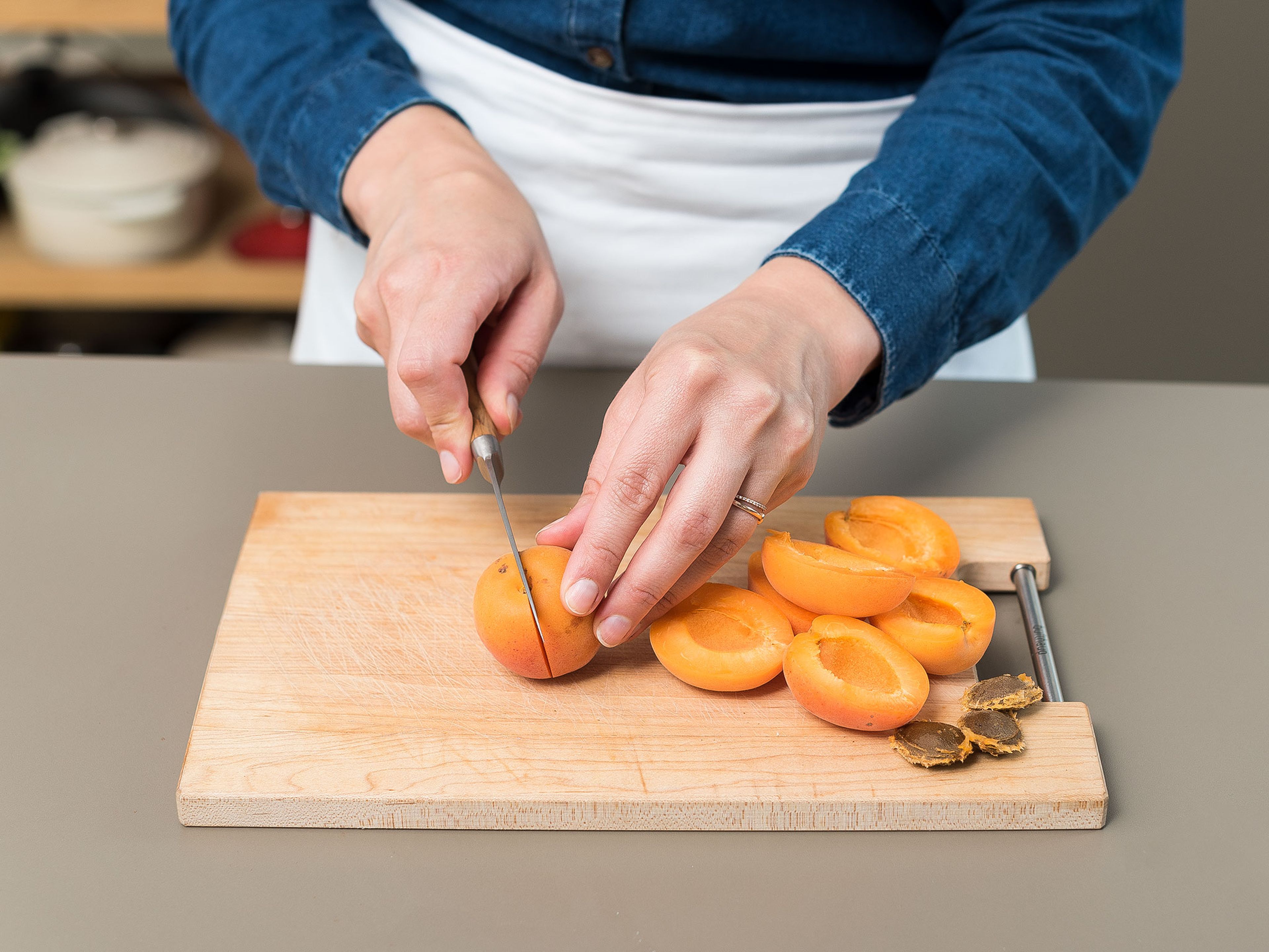 Preheat oven to 200°C/400°F, and grease the tart pan. Melt butter in a small pot over low heat, and set aside to cool. Wash apricots and dry, remove pit with a sharp knife, and cut in halves.