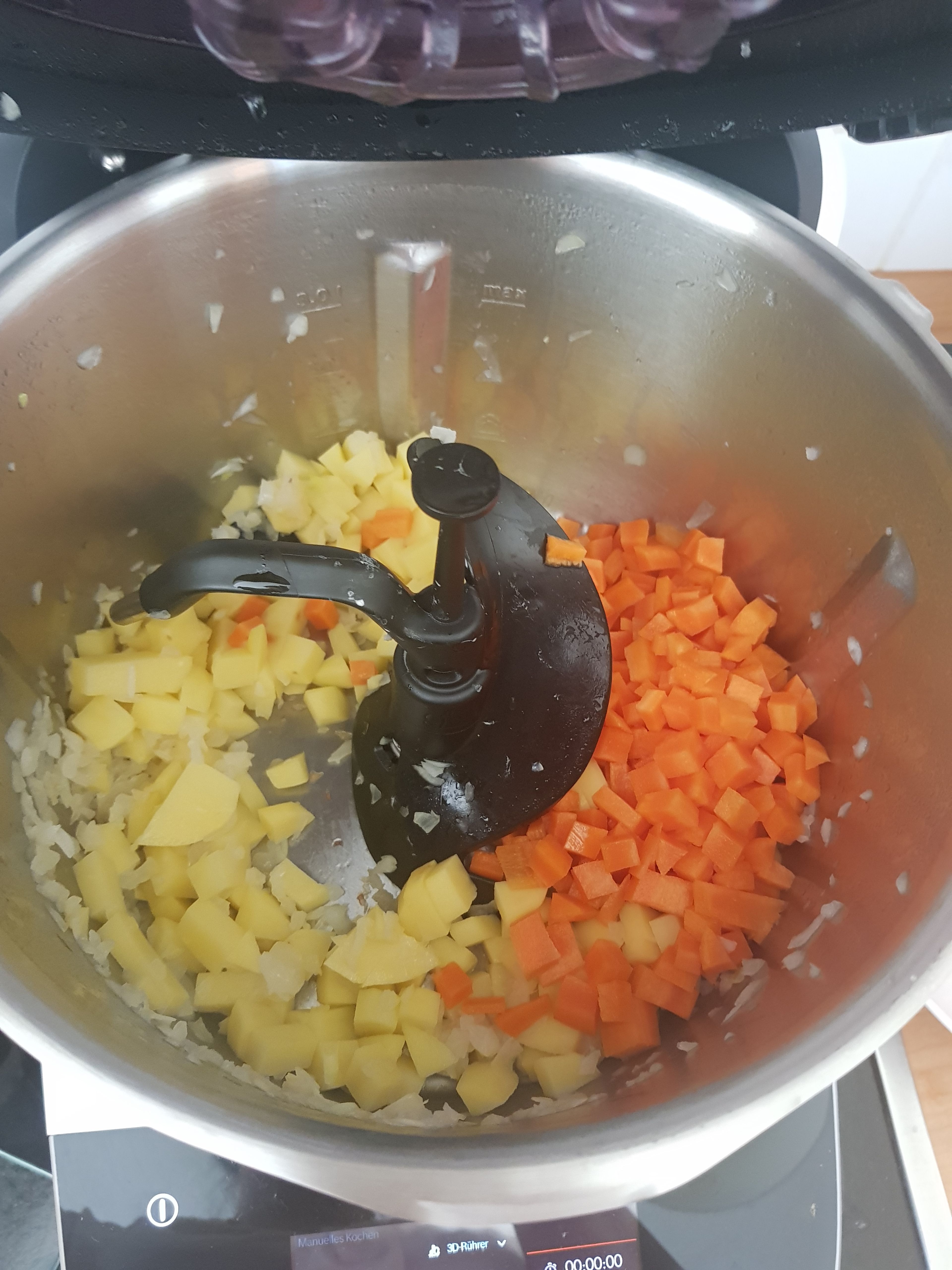 Die Kartoffeln, Karotten und Tomaten in ca. 0,5 cm kleine Würfel schneiden und beiseite stellen. Universalmesser einsetzen, die Zwiebeln in den Cookit geben, den Deckel mit Messbecher schließen und zerkleinern (Universalmesser | Stufe 12 | 5 Min.). Universalmesser entfernen und 3D-Rührer einsetzen. Das Öl einwiegen und die Zwiebeln in Öl bei geschlossenem Deckel, ohne Messbecher, anrösten (3D-Rührer | Stufe 5 | 160°C |4 Min.). Kartoffeln und Karotten in den Topf geben, Deckel ohne Messbecher schließen und mit anbraten (3D-Rührer | Stufe 5 | 160°C | 3:30 Min.).