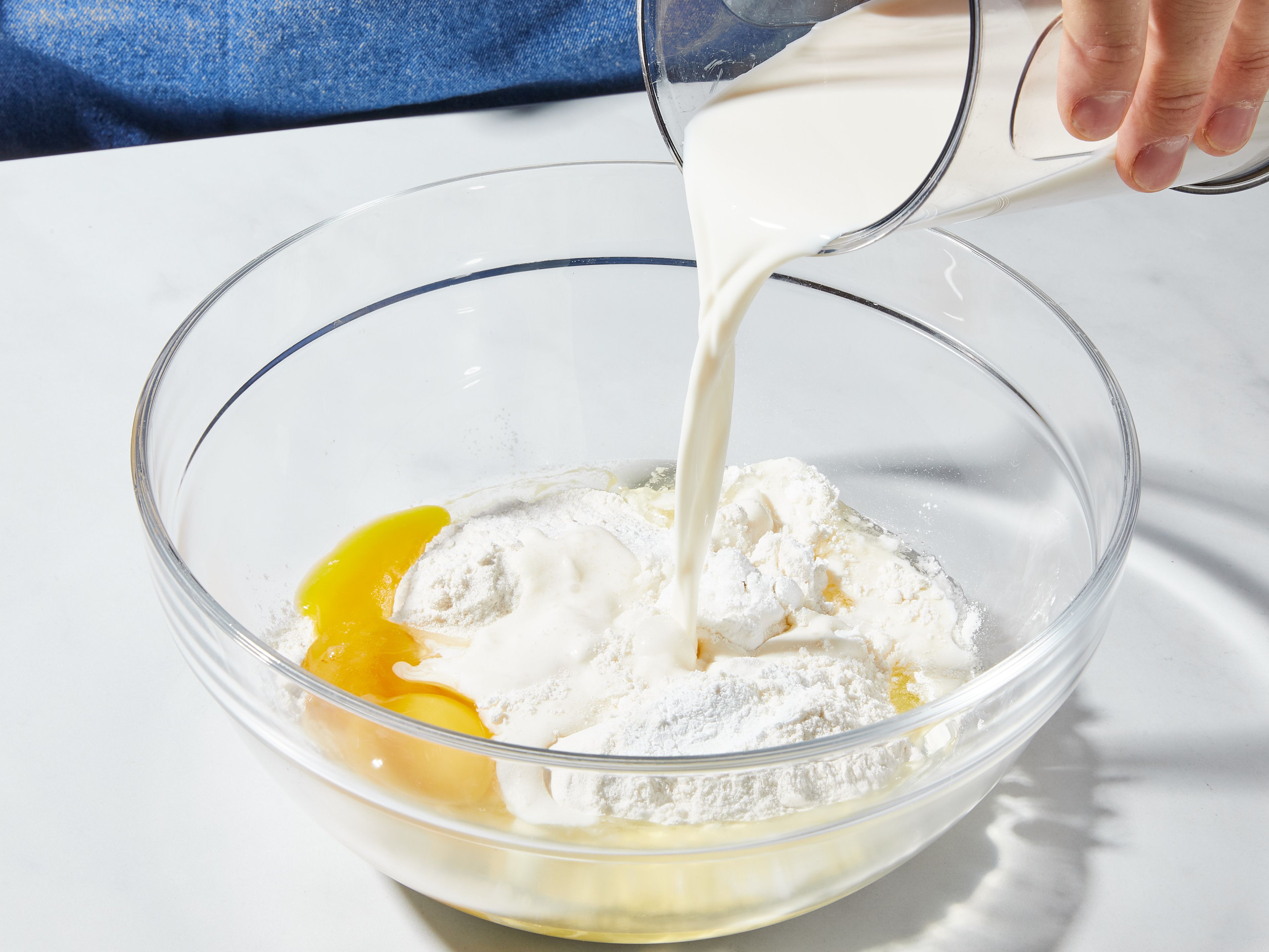 Den Backofen auf 180°C Ober-/Unterhitze vorheizen. Mehl, Backpulver, Zucker und Salz in einer großen Rührschüssel mischen und beiseitestellen. Eier und Milch in einem kleinen Messbecher verquirlen. Dann die Hälfte der geschmolzenen Butter einrühren. Die Milchmischung vorsichtig in die trockenen Zutaten einrühren, aber nur so viel, dass alles gerade so vermengt ist (ein paar kleine Klümpchen dürfen sein). Wenn der Teig zu dickflüssig erscheint, etwas mehr Milch zugeben.