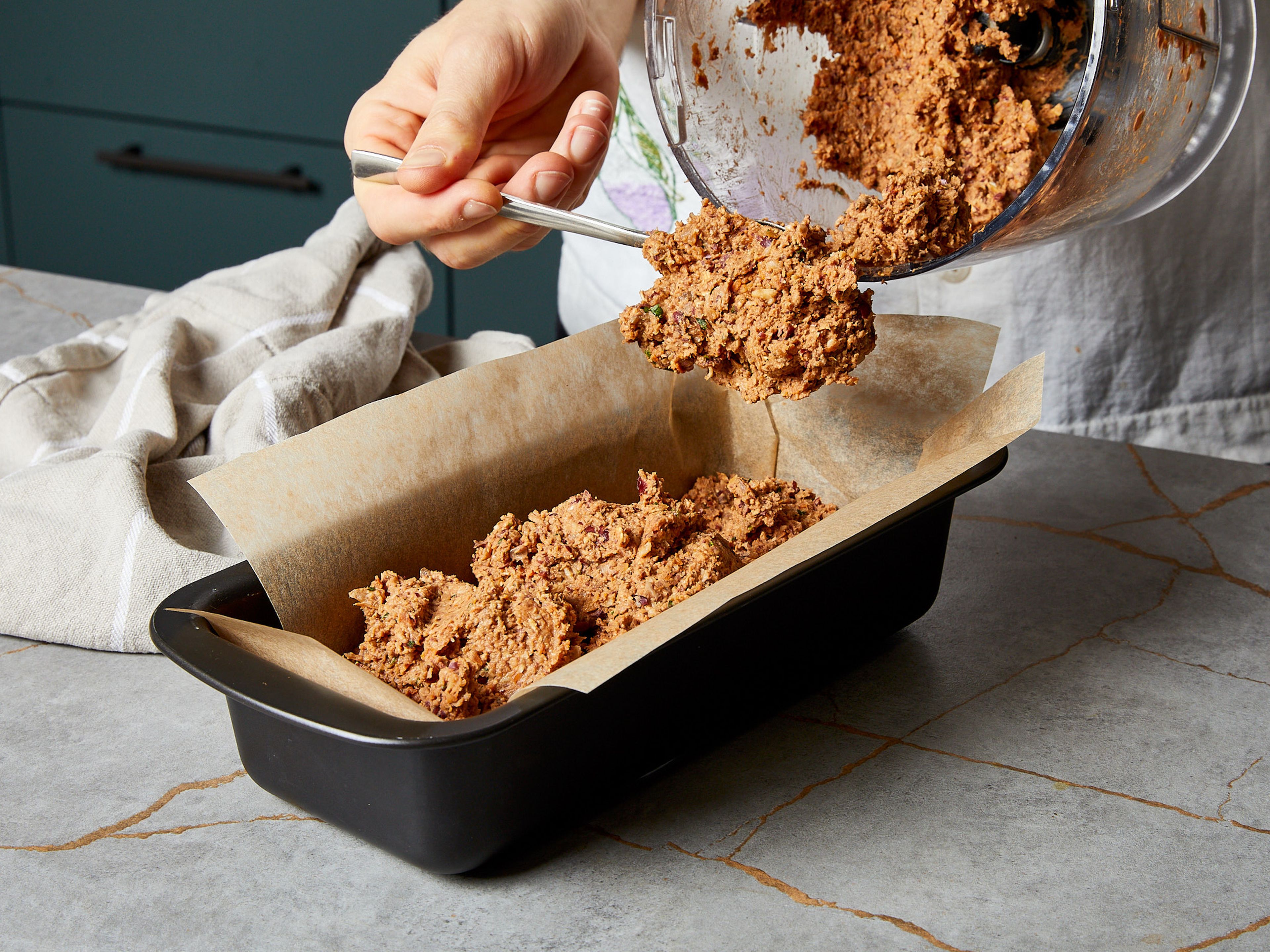 Place a sheet of parchment paper in a loaf tin (20 cm/8 inch) with the long ends extended from the sides (to easily lift vegan roast out of the tin). Pour the chopped mixture into the loaf tin, press it down a little and smooth the surface. Bake vegan roast in the oven at 200°C/390°F for approx. 25 min.