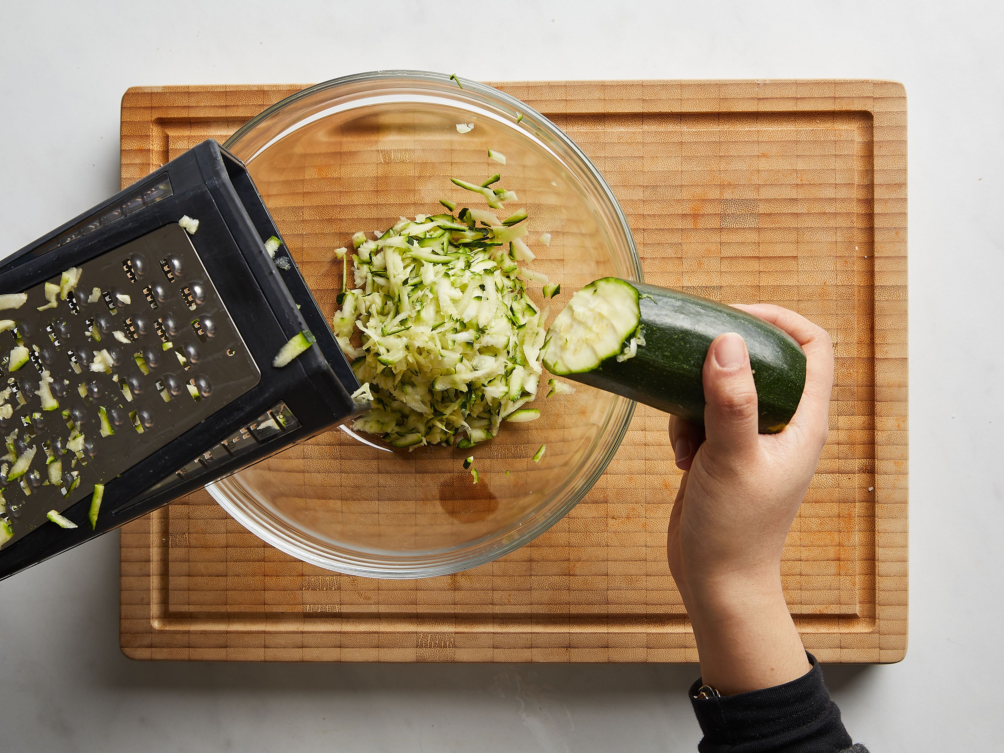 Set a large pot of water to boil over medium-high heat. Trim ends of zucchini, and use the large holed-side of a box grater to grate the zucchini into a clean towel set inside a bowl. Use the towel to help you squeeze out as much of the extra water from the grated zucchini; discarding the liquid. Zest and juice lemon. Pluck mint leaves and thinly slice. Crumble feta cheese into a bowl.