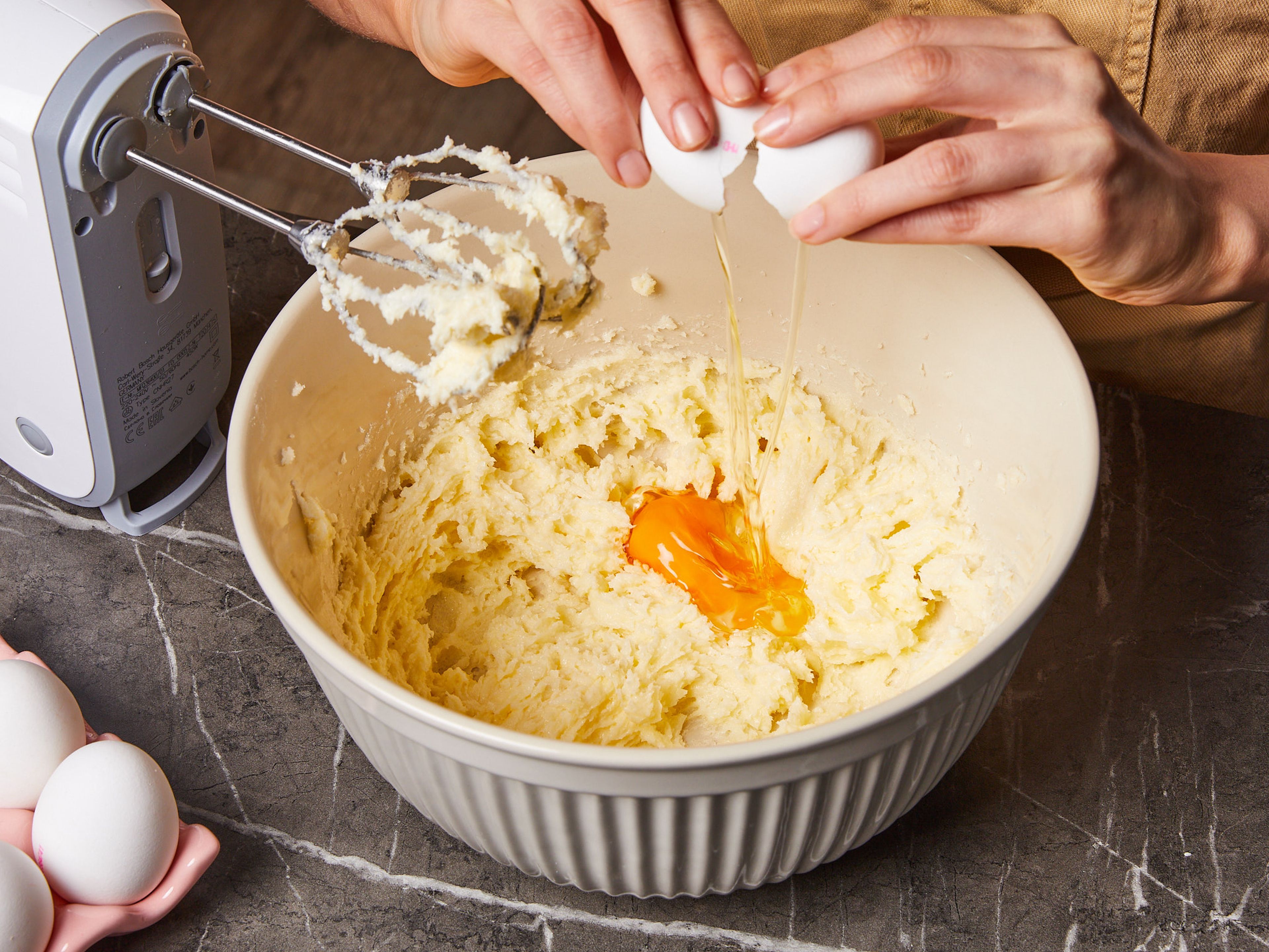 For this fluffy cake, preheat the oven to 180°C/350°F. In a bowl, beat butter, sugar, and vanilla extract with a hand mixer with beaters until creamy. Add eggs one by one and mix until everything is smooth. Finely grate lemon zest and stir it into the mix.