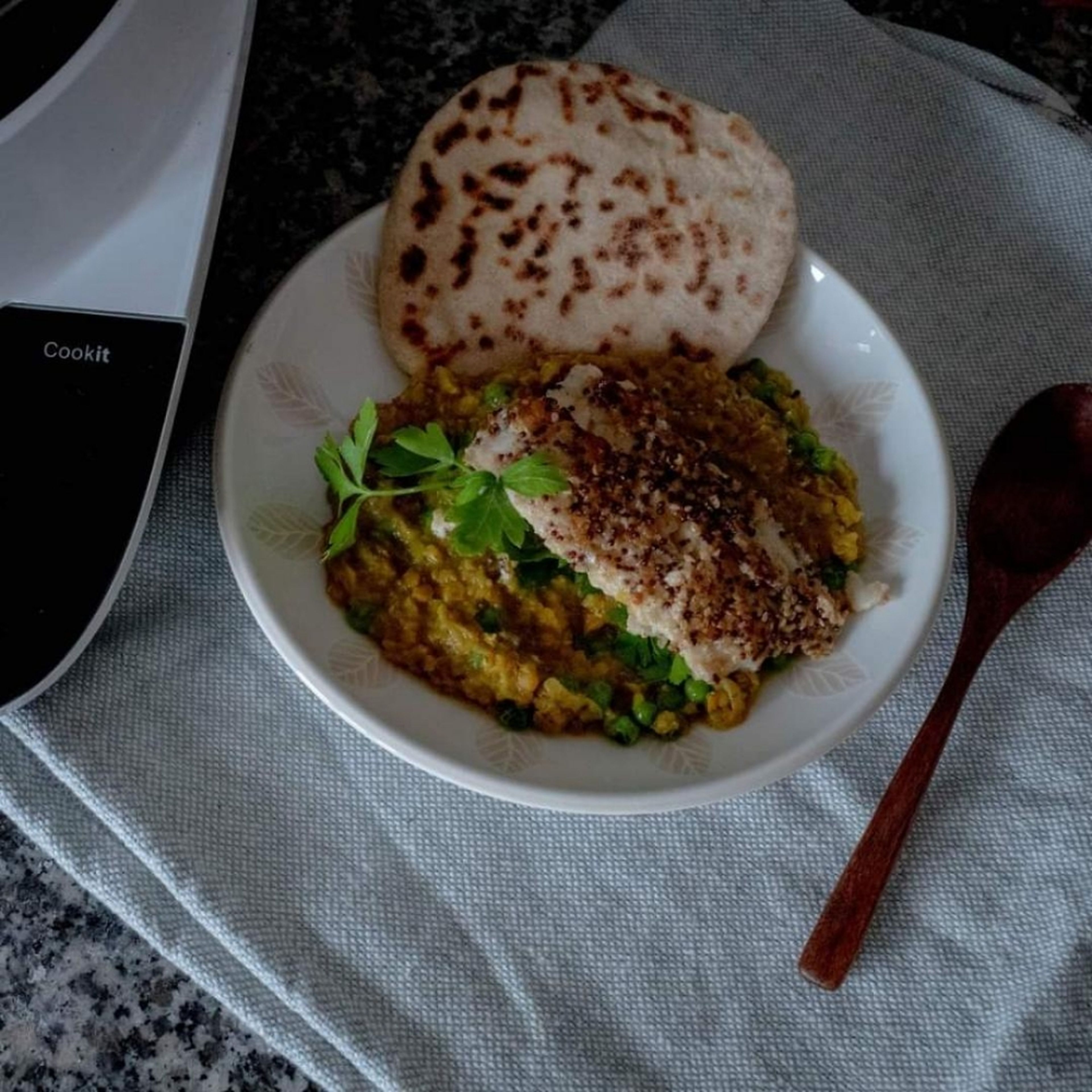 Die Linsen bei Bedarf noch einmal erhitzen. Salzen. evtl mit Chili etwas schärfen. Portion In einem tiefen Teller geben. Ein Fischfilet mit der panierten Seite nach oben darauf geben. Mit Naanbrot servieren.