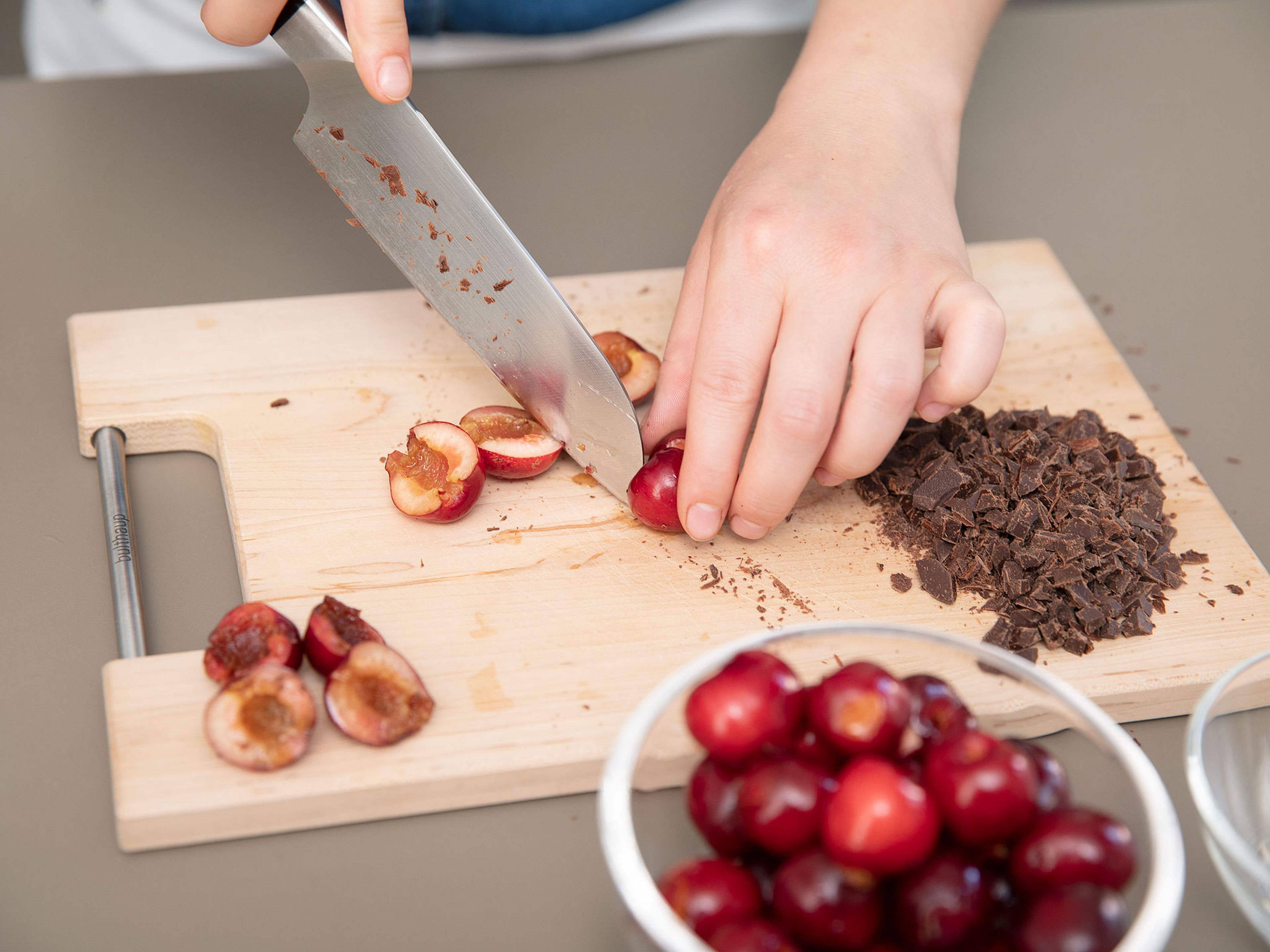 Schokolade fein hacken. Kirschen halbieren, entkernen und in kleine Stücke schneiden. In den Teig geben und vermengen.