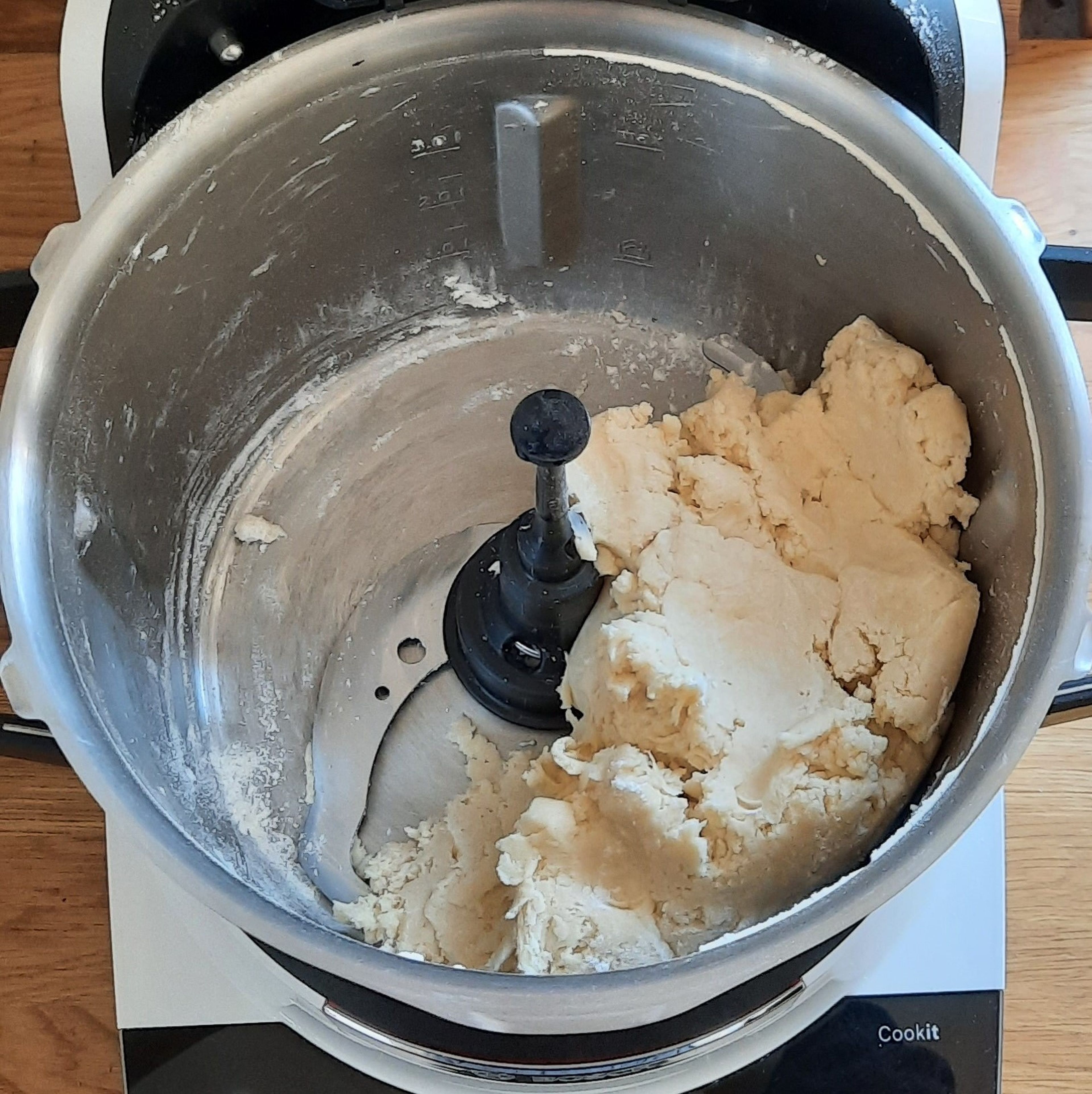 Universalmesser in den Cookit einsetzen. Mehl und Butter einwiegen, den Deckel schließen, den Messbecher einsetzen und verkneten (Universalmesser | Stufe 11 | 50 Sek.). Messbecher abnehmen, 130 ml kaltes Wasser darin einfüllen und schlückchenweise hinzugeben.