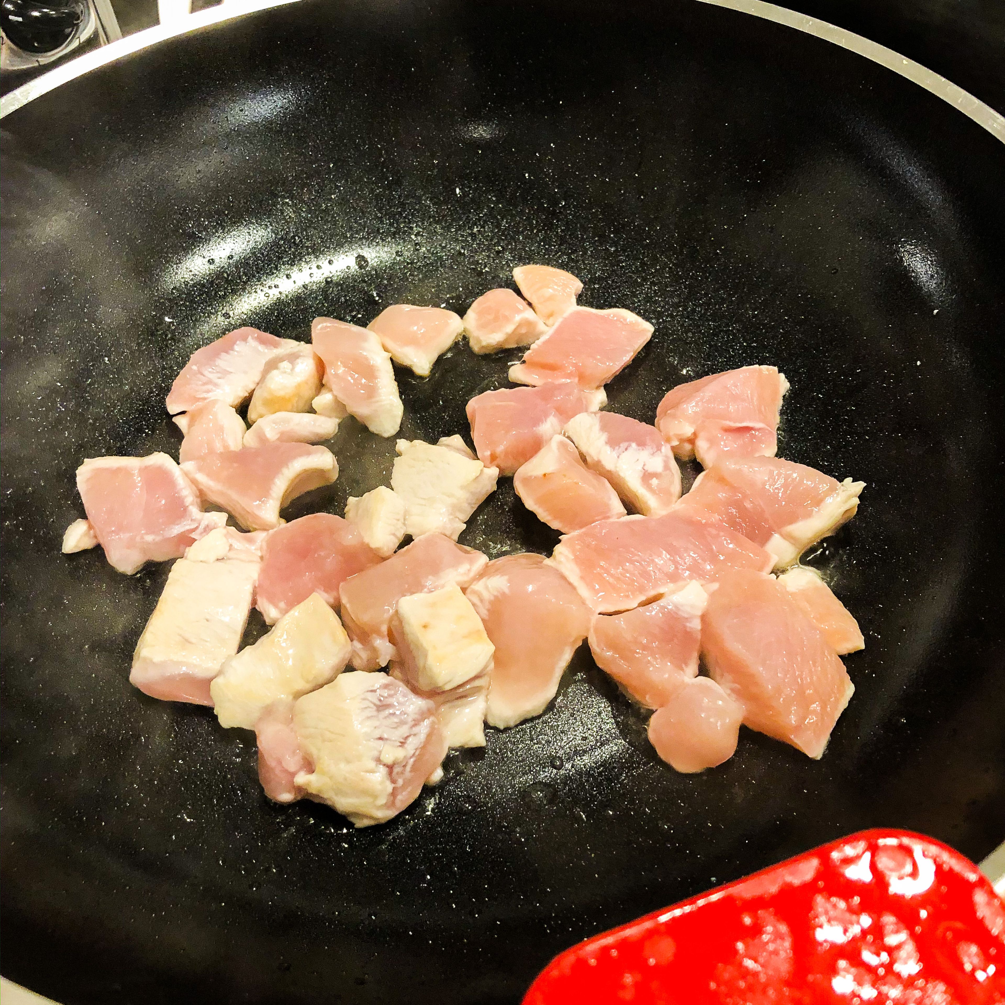 Das Hähnchenbrustfilet in kleine Stücke schneiden und in einem Wok mit etwas Öl anbraten. Hierbei sollte das Fleisch nicht auswässern. Das gebratene Fleisch aus dem Wok nehmen und zur Seite stellen.