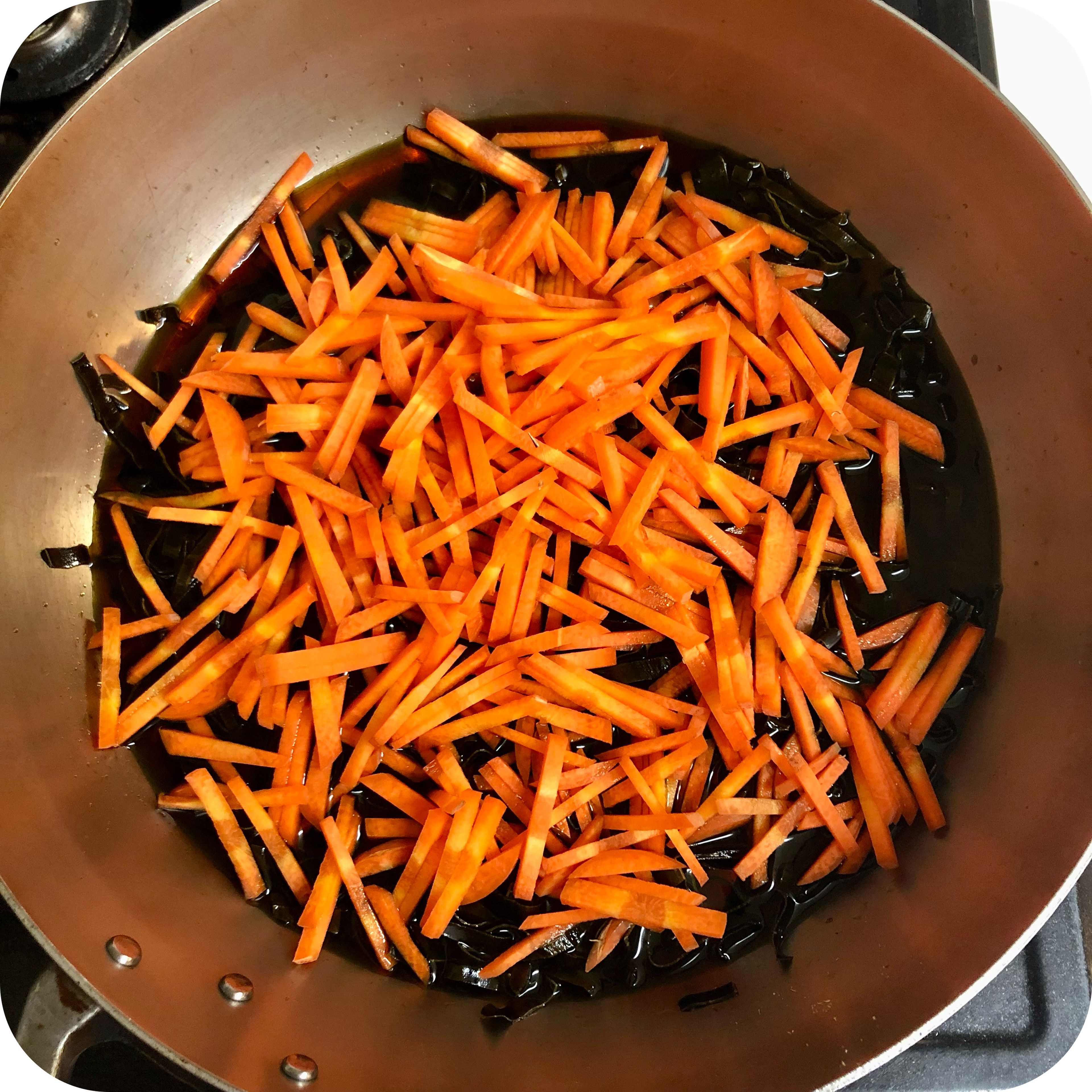 Saute soy sauce, mirin, kombu, and carrot in a frying pan.