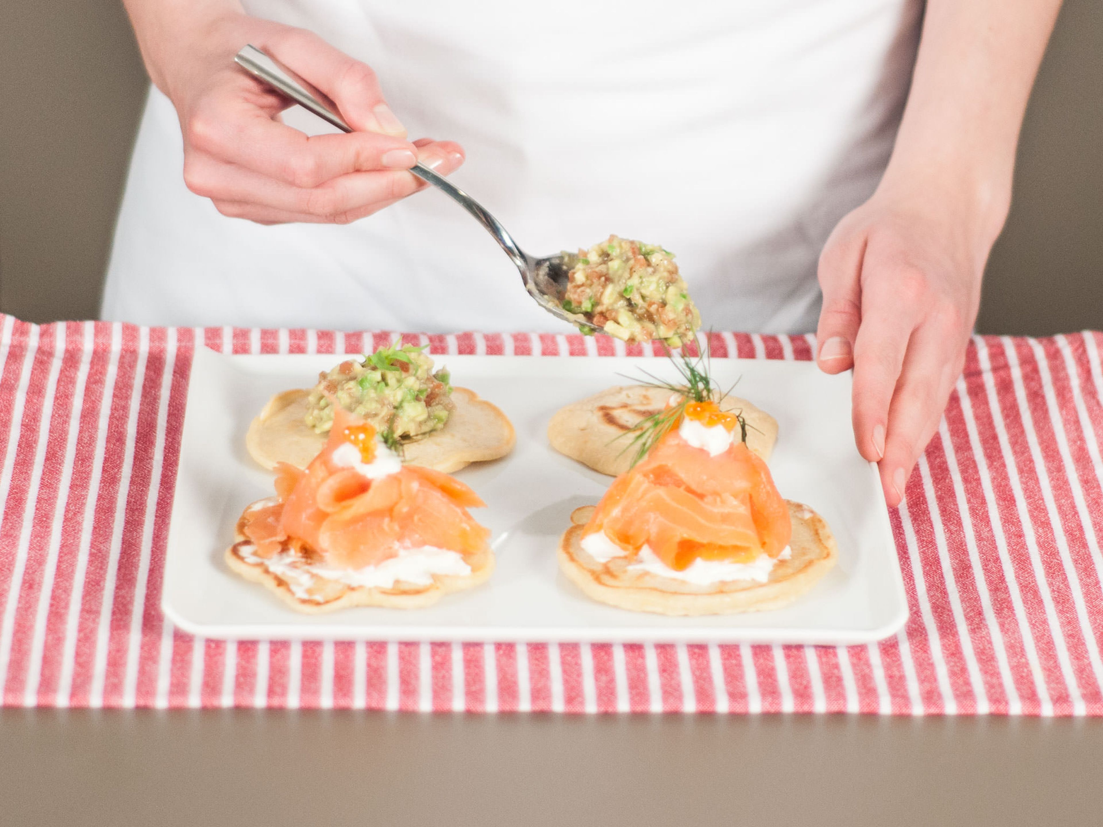 Garnish half of the blinis with a dollop of cream cheese. Divide salmon into bite-sized pieces. Place salmon on cream cheese and top with caviar. Place avocado-tomato tartare on the rest of blinis. Serve with more dill if desired. Enjoy as a starter, breakfast or snack.