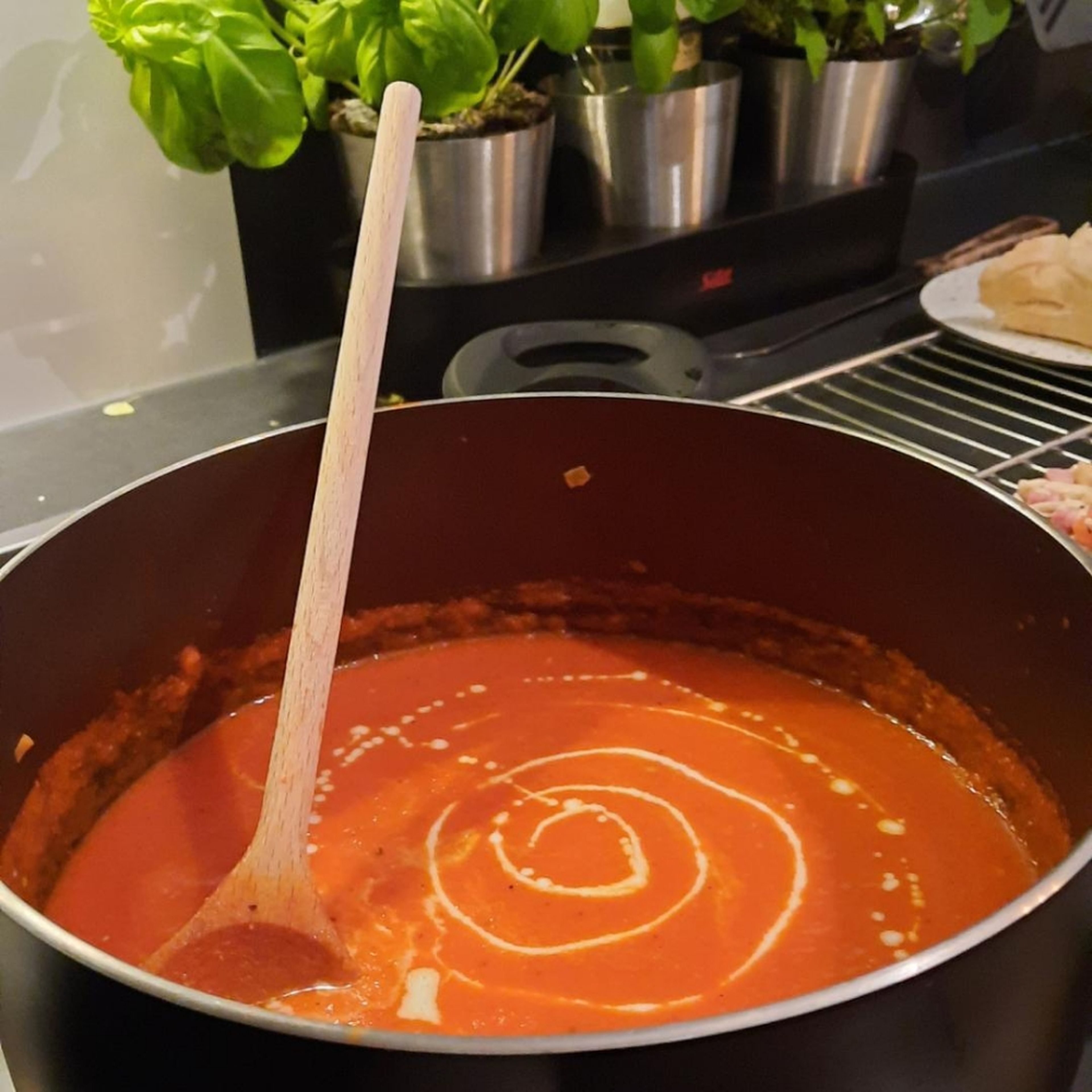 Sahne zu der Suppe geben und alles gut verrühren. Suppe in Suppenschüsseln füllen und mit Sahne, Basilikum und Croutons servieren.