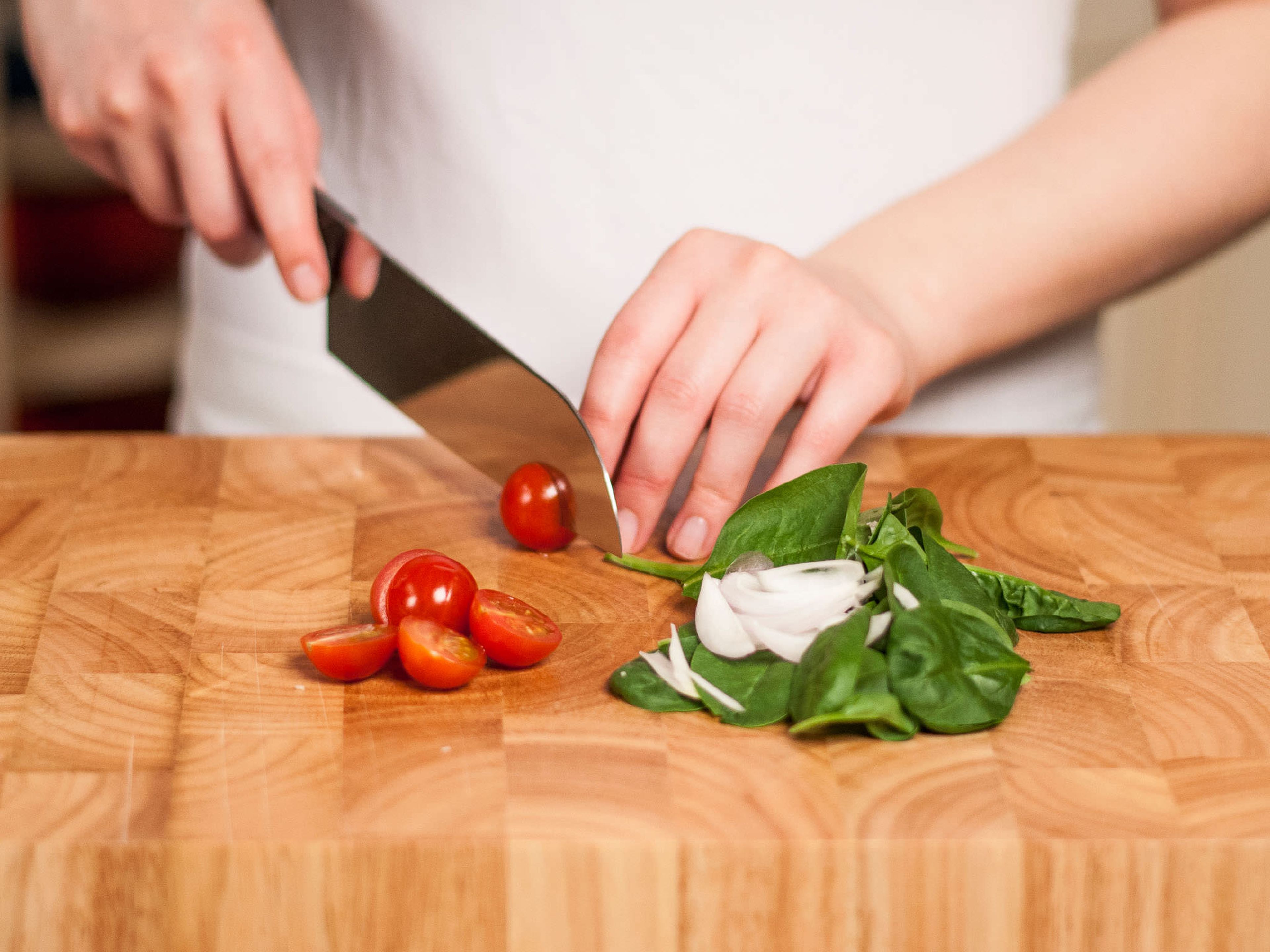 Clean spinach. Cut onion into thin strips, finely chop garlic, and halve cherry tomatoes.