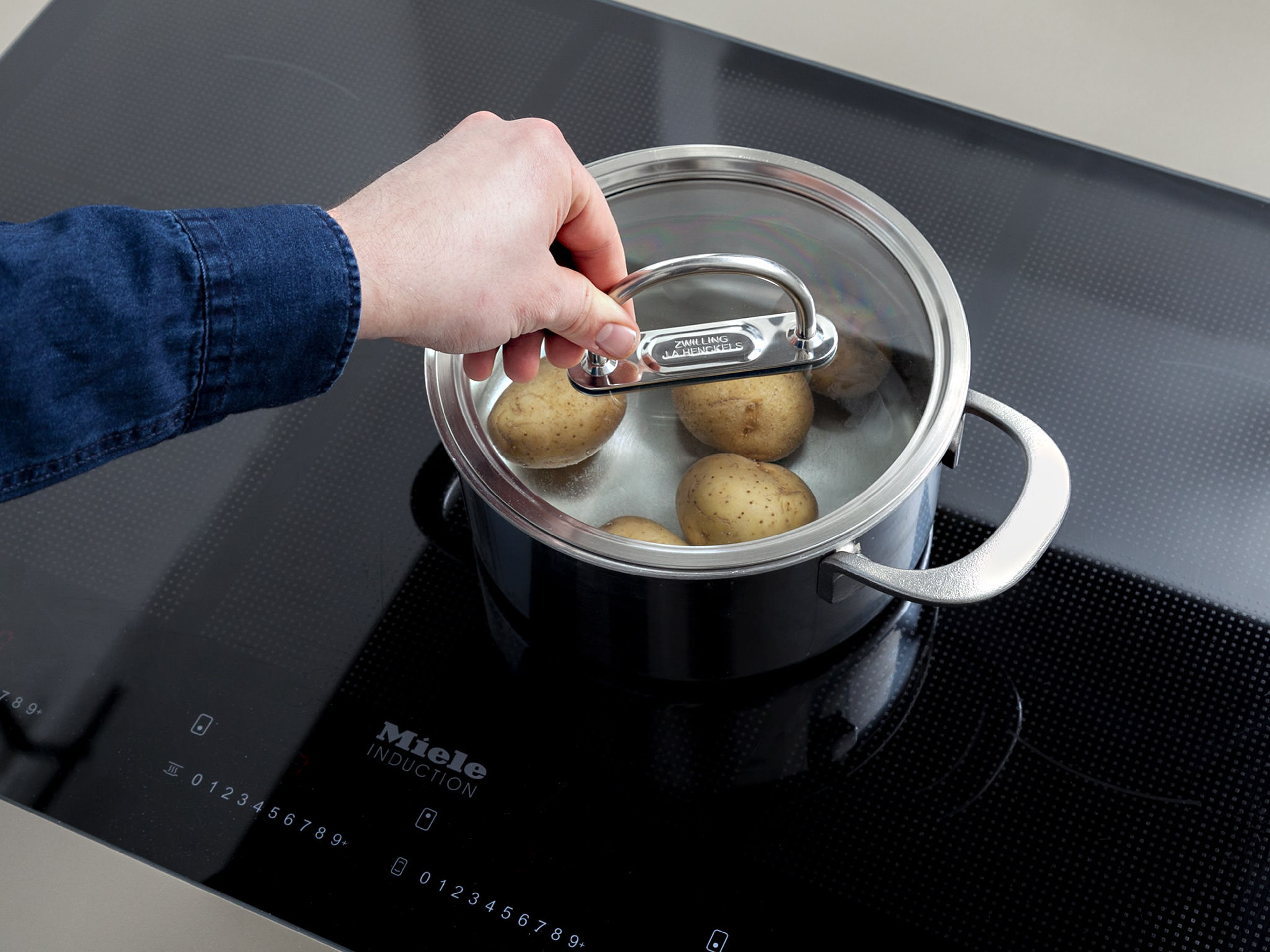Wasser in einem Topf zum Kochen bringen. Salz und Frühkartoffeln in den Topf geben und für ca. 10 Min. kochen. Abgießen und Kartoffeln pellen, beiseitestellen und abkühlen lassen.