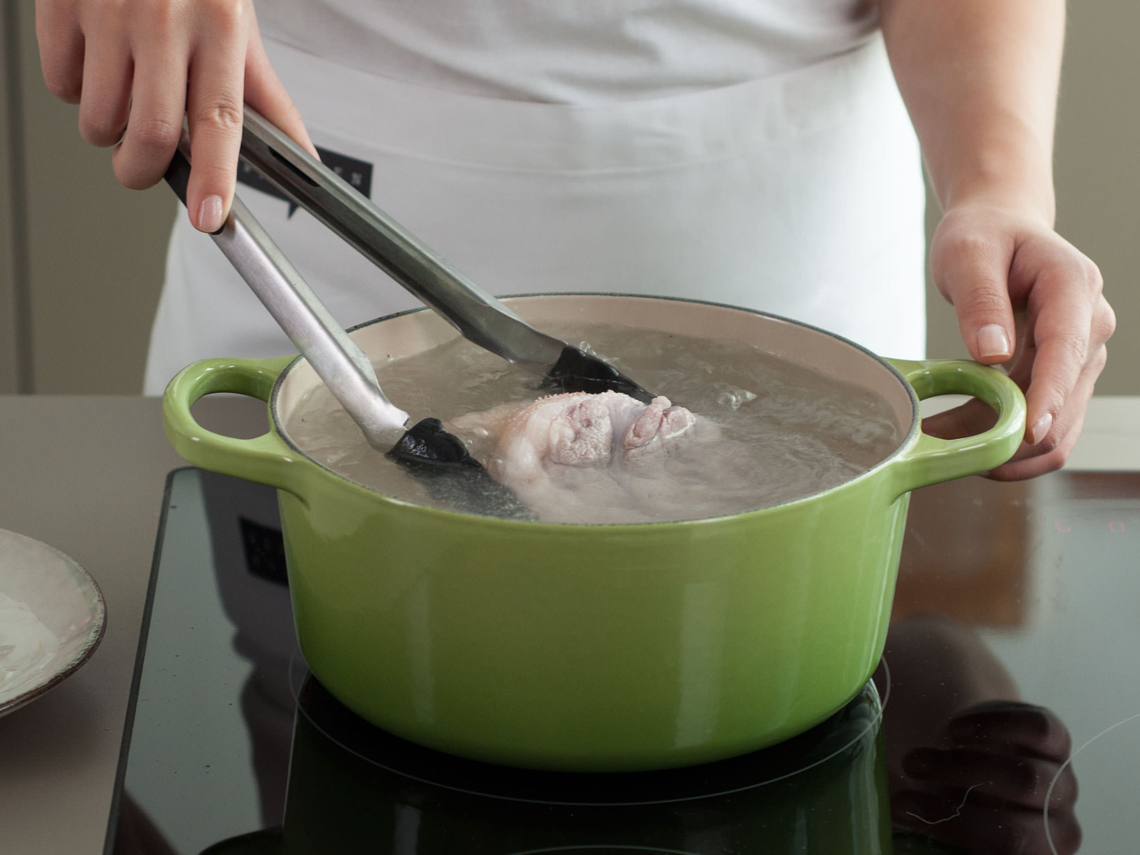Topf mit Wasser füllen, so dass die Schweinshaxe komplett bedeckt ist. Das Wasser bei starker Hitze zum Kochen bringen und Schweinshaxe in den Topf geben.