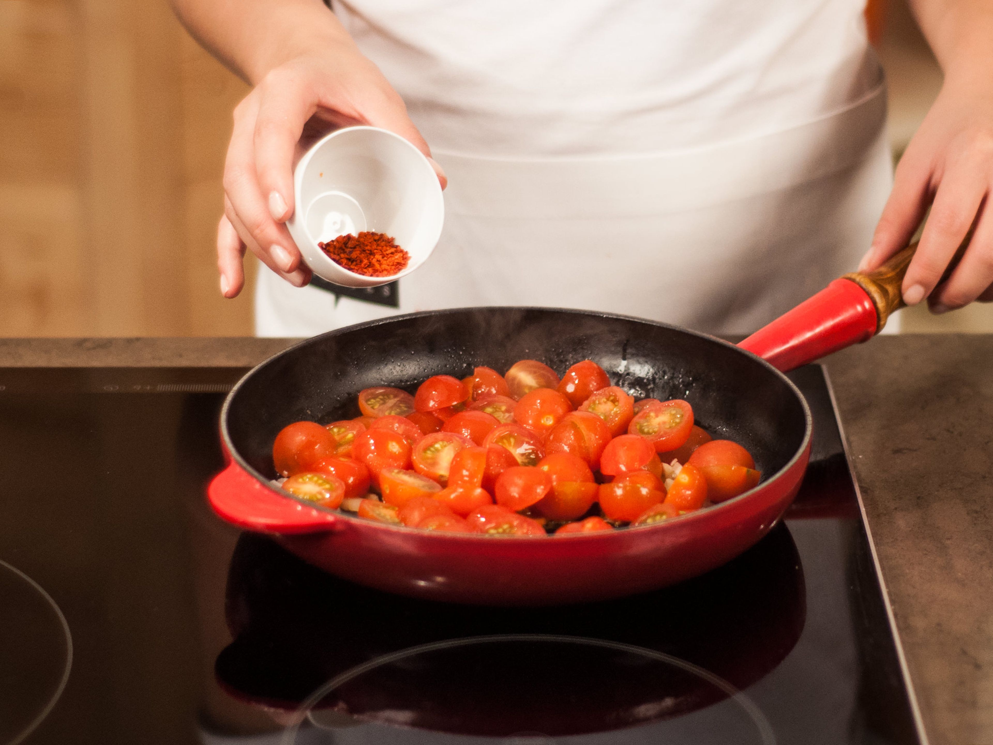 In einer Pfanne die Schalotten zusammen mit dem Knoblauch glasig anschwitzen. Tomaten und Zucker hinzugeben. Mit Salz, Pfeffer und Chilipulver abschmecken.