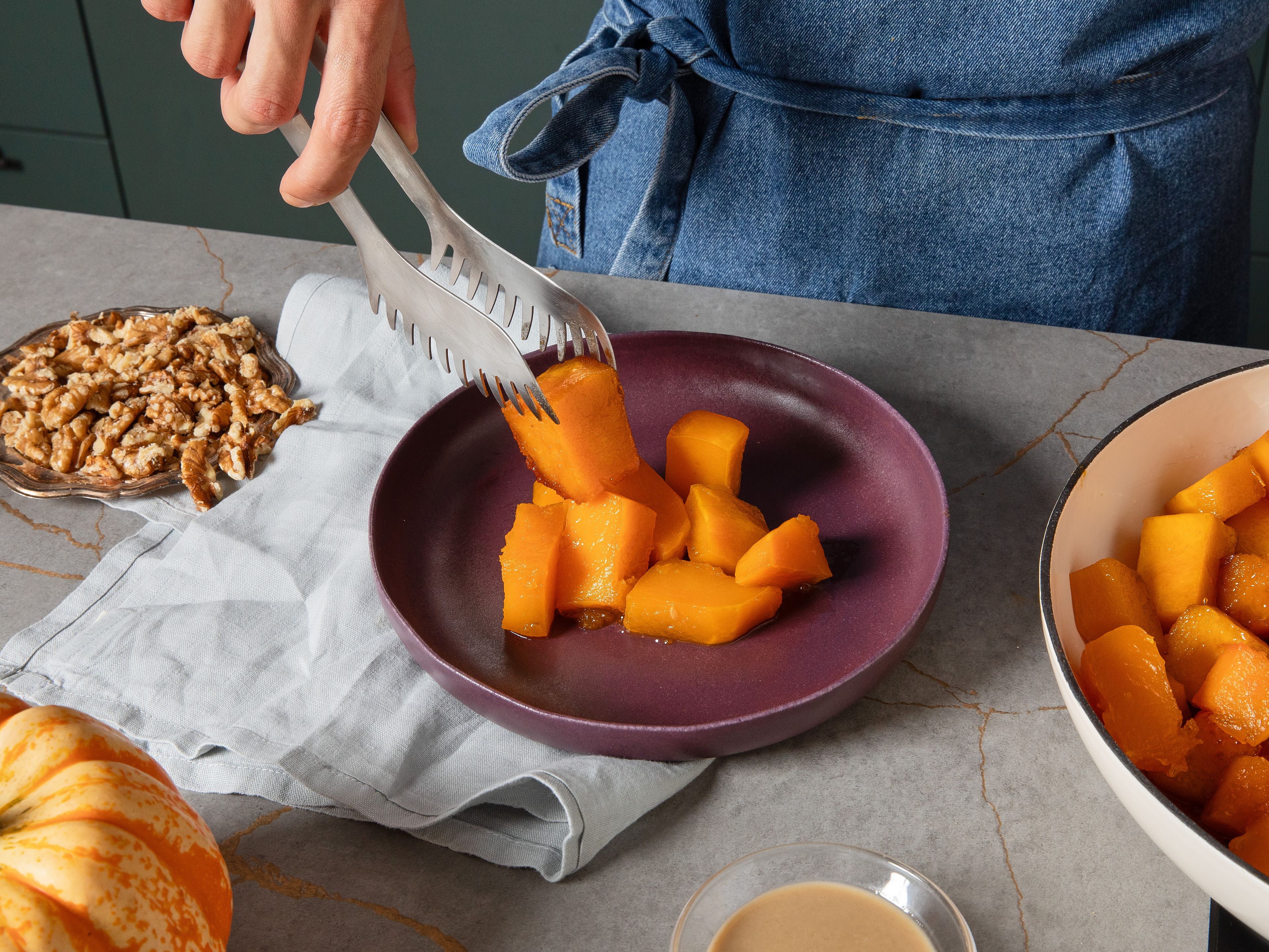 Gegen Ende der Garzeit mit einer Gabel prüfen, ob die Stücke zart sind. Dann von der Hitze nehmen, sobald sie weich sind und der Zucker größtenteils aufgenommen wurde. Den Kürbis auf eine Servierplatte geben und ca. 5 Min. abkühlen lassen. Zum servieren mit Tahini, gehackten Walnüssen und nach Belieben mit Eiscreme nach Geschmack servieren.