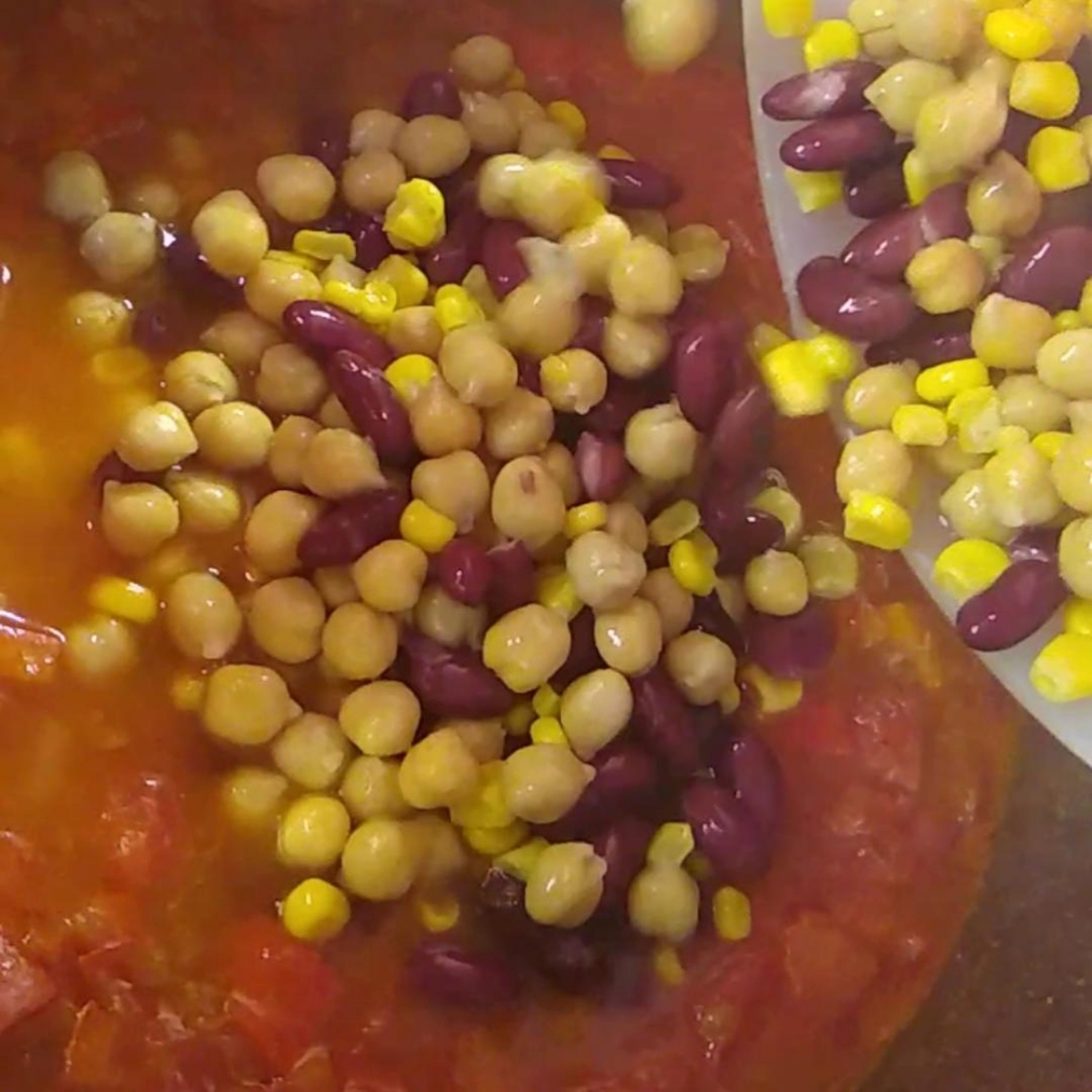 Die Kichererbsen, Mais und die Kidneybohnen in einem Sieb gut abtropfen lassen. Wenn die Kochzeit (vom köcheln) um ist, hinzufügen und mit dem Chilipulver würzen, weiter 5min köcheln lassen.