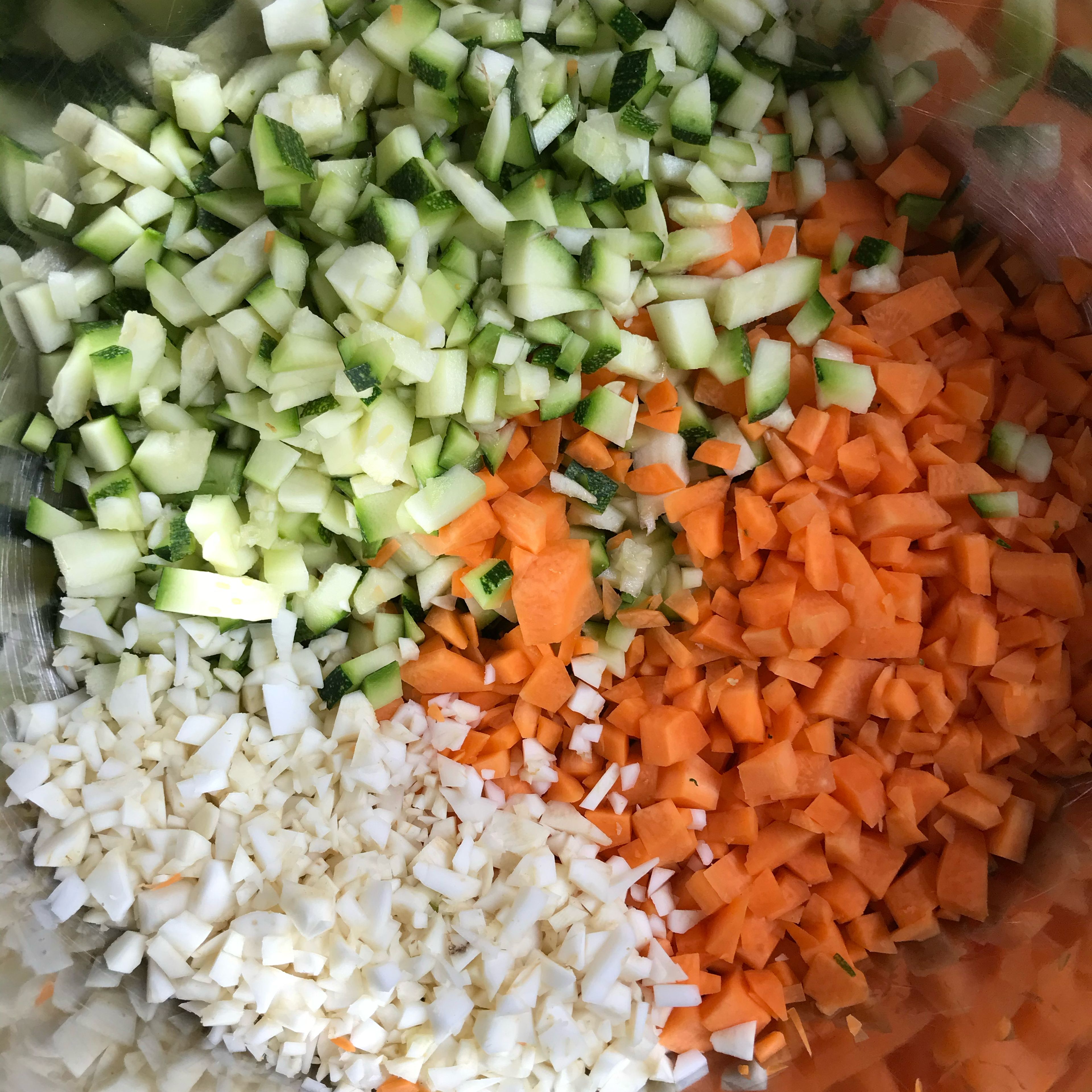 Zucchini, Karotte, Petersilienwurzel, Lauch, Knoblauch und eine Zwiebel fein hacken. Die zweite Zwiebel im Ringe schneiden und beiseite stellen.
