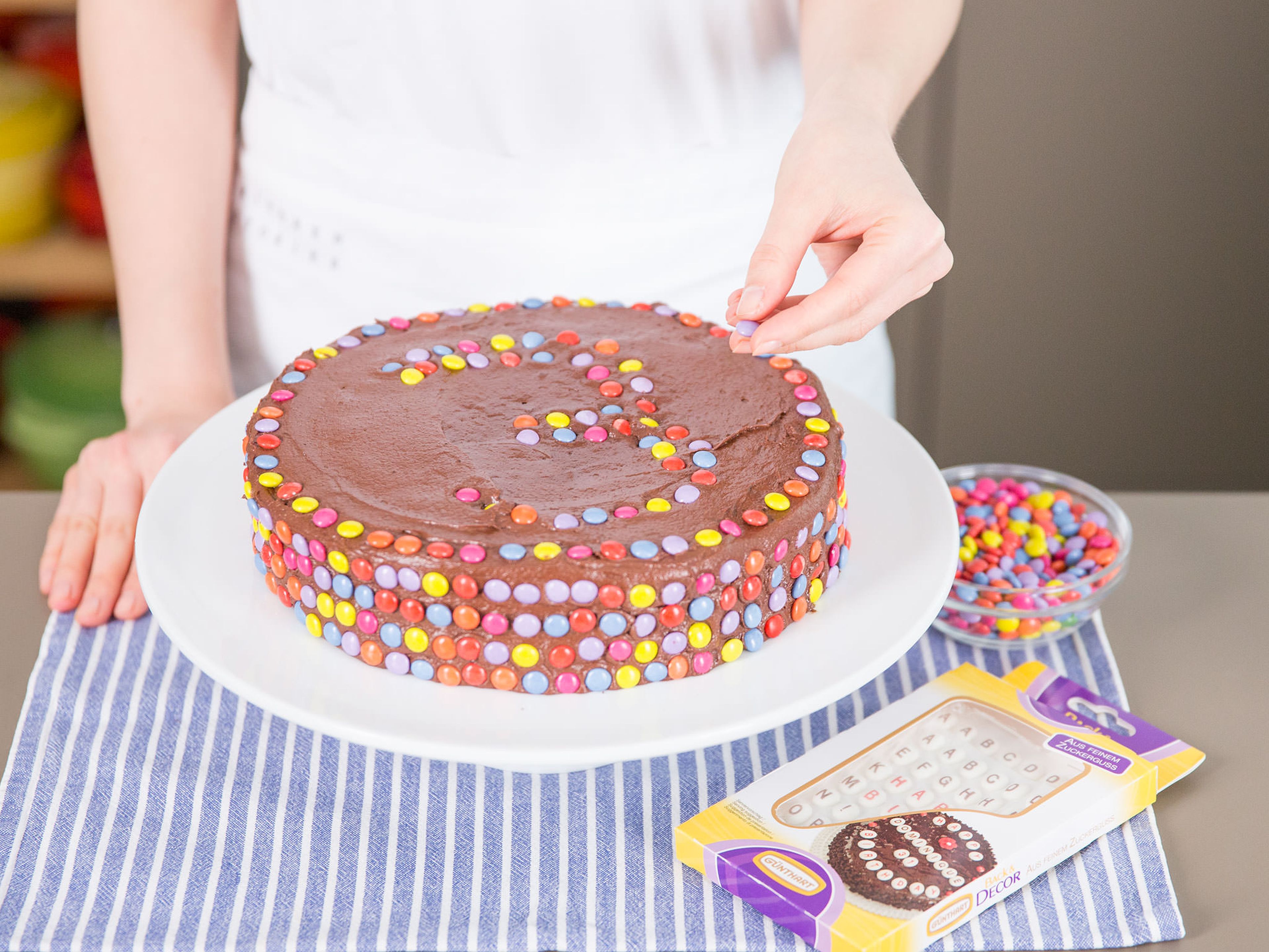Frost cooled cake with buttercream and cover in Smarties by gently pressing the candies into buttercream.