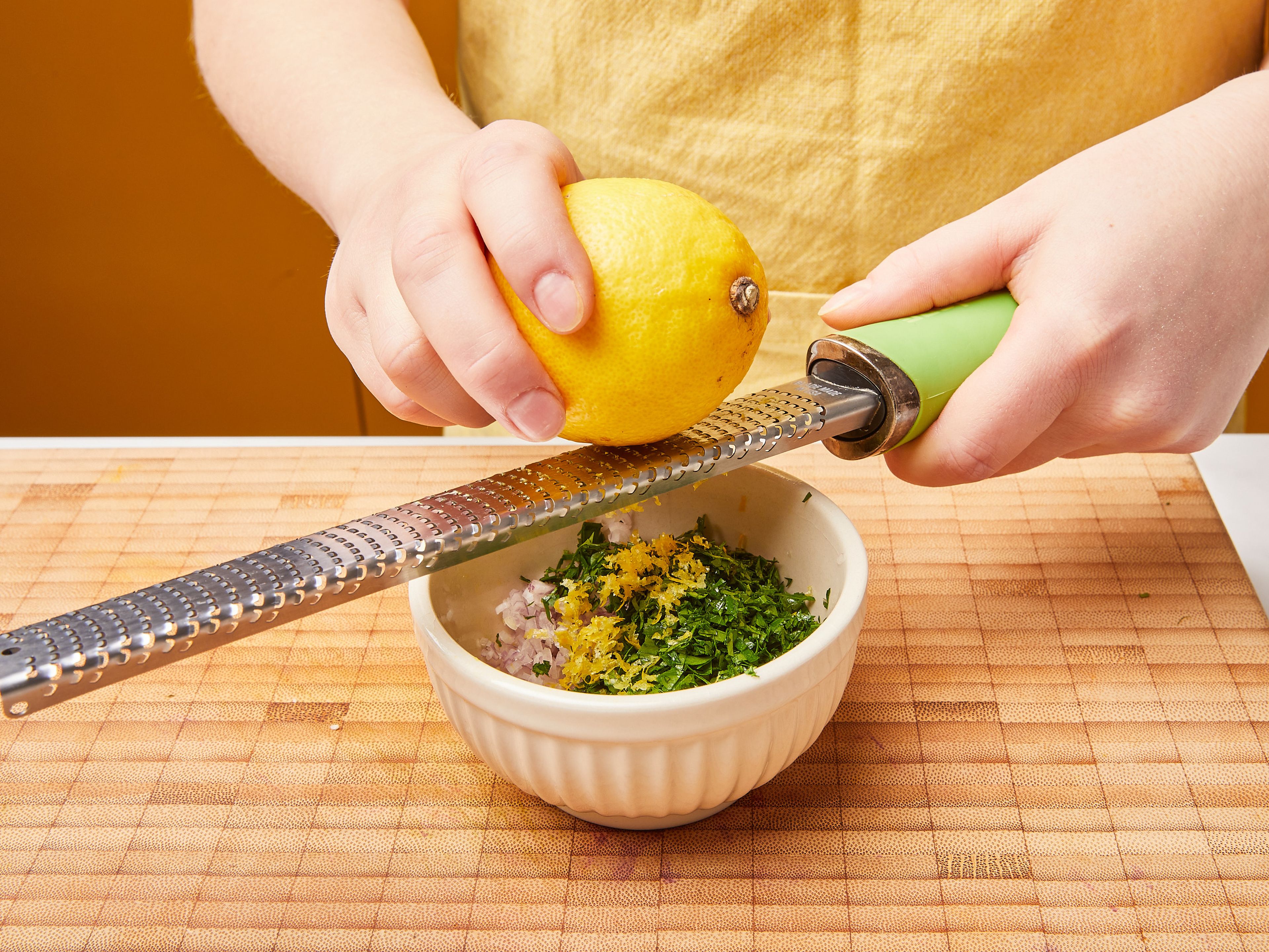 Während der Blumenkohl kocht, die Gremolata zubereiten. Die Schalotte fein würfeln, dann die Petersilie hacken. Die Zitrone abreiben und auspressen. Dann alles in eine Schüssel geben, zusammen mit der restlichen Orangenschale und dem restlichen Olivenöl. Gut vermischen.