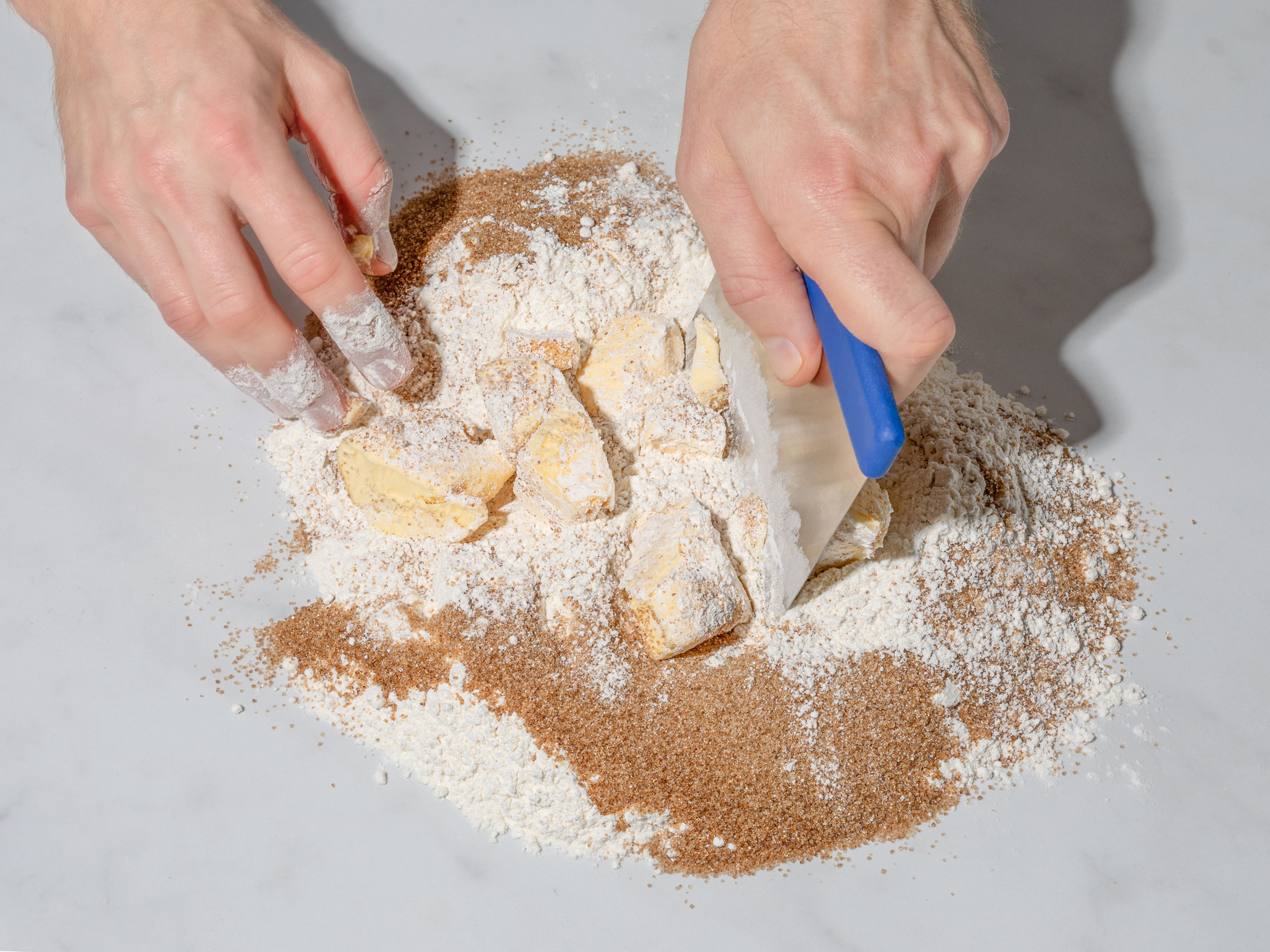 Für den Teig Mehl, braunen Zucker und Salz auf eine saubere Arbeitsfläche geben und in die Mitte eine Mulde drücken. Weiche Butter in Stücken und geriebenen Ingwer in die Mulde geben. Die Zutaten mit dem Teigschaber langsam miteinander vermengen. Sobald ein grober Teig entstanden ist, alles mit den Händen zu einem geschmeidigen Teig kneten. Teig in Frischhaltefolie wickeln und für ca. 30 Min. im Kühlschrank ruhen lassen.