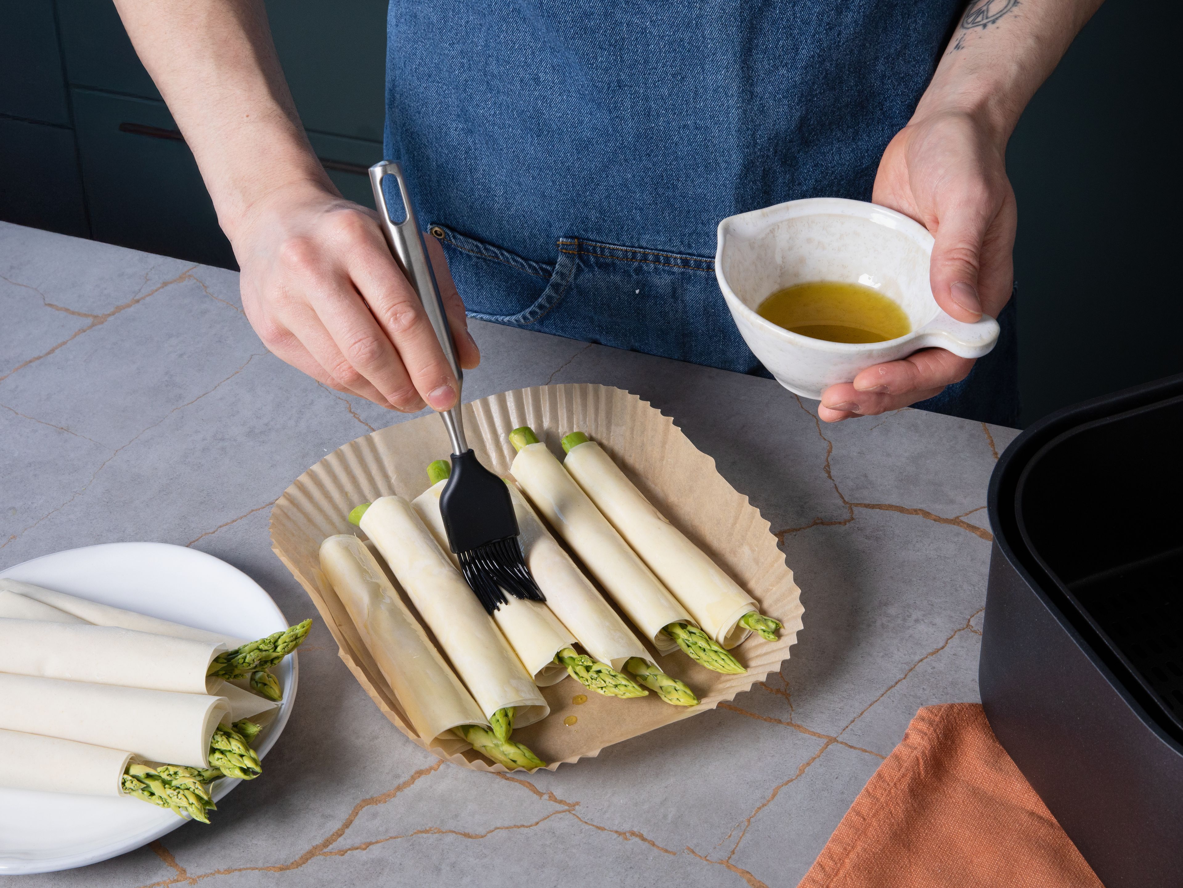 Brush the pastry rolls with olive oil and sprinkle with a bit more Parmesan. Preheat the air fryer to 200  °C. Place the rolls in the basket in batches and cook for approx. 8–10 min. until golden and crispy.