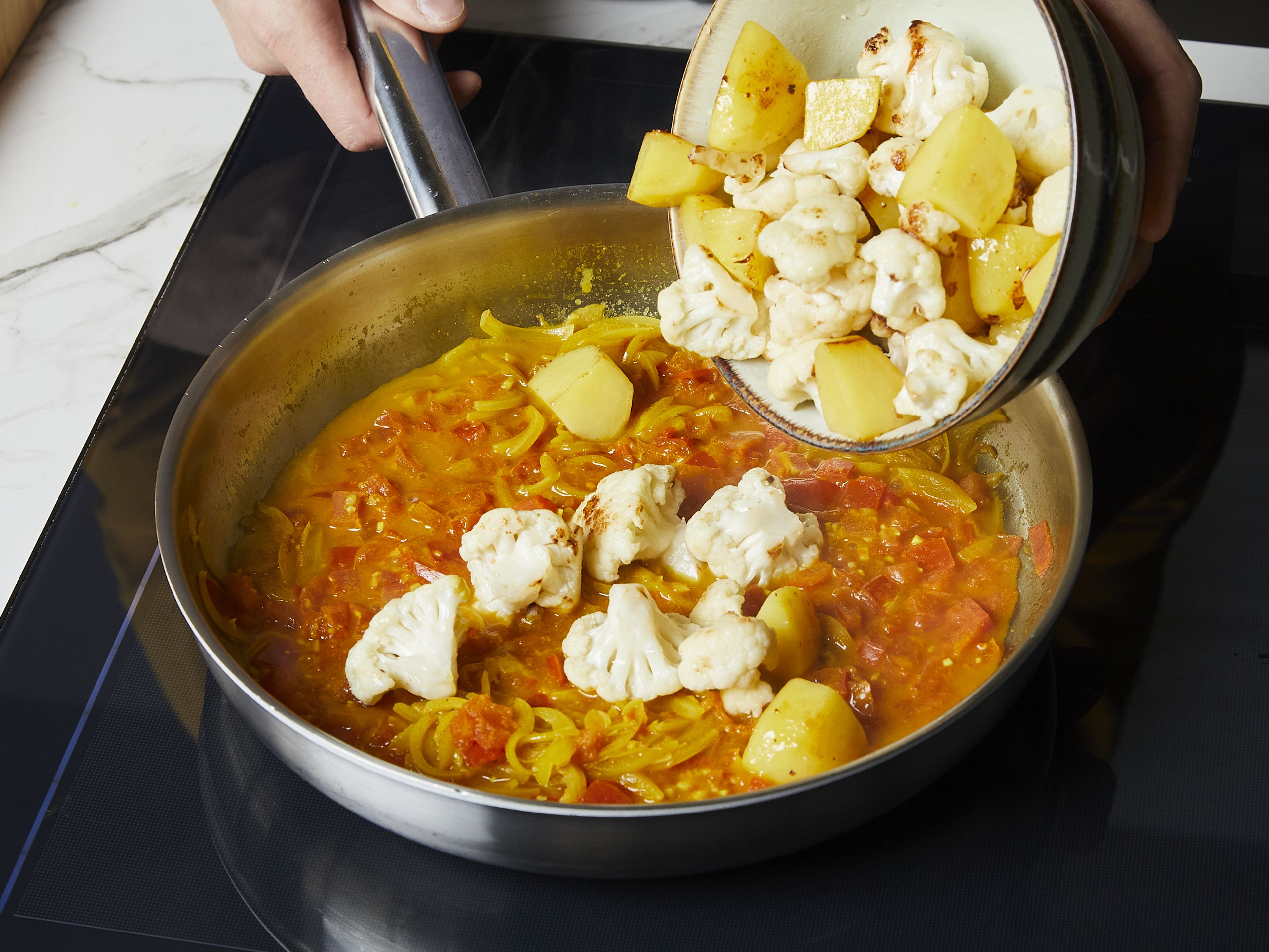 Dann Kartoffeln und Blumenkohl hinzugeben, mischen und mit Salz und Pfeffer würzen. Zugedeckt bei mittlerer Hitze ca. 14–16 Min. kochen, bis die Kartoffeln und der Blumenkohl weich sind. Wenn das Curry zu trocken ist, etwas Wasser hinzufügen. Immer nur so viel zugeben, dass das Gemüse gar werden kann. In der Zwischenzeit den Koriander hacken. Das fertige Curry auf tiefen Tellern anrichten, mit Koriander bestreuen und nach Belieben mit gekochtem Reis oder Naan servieren.