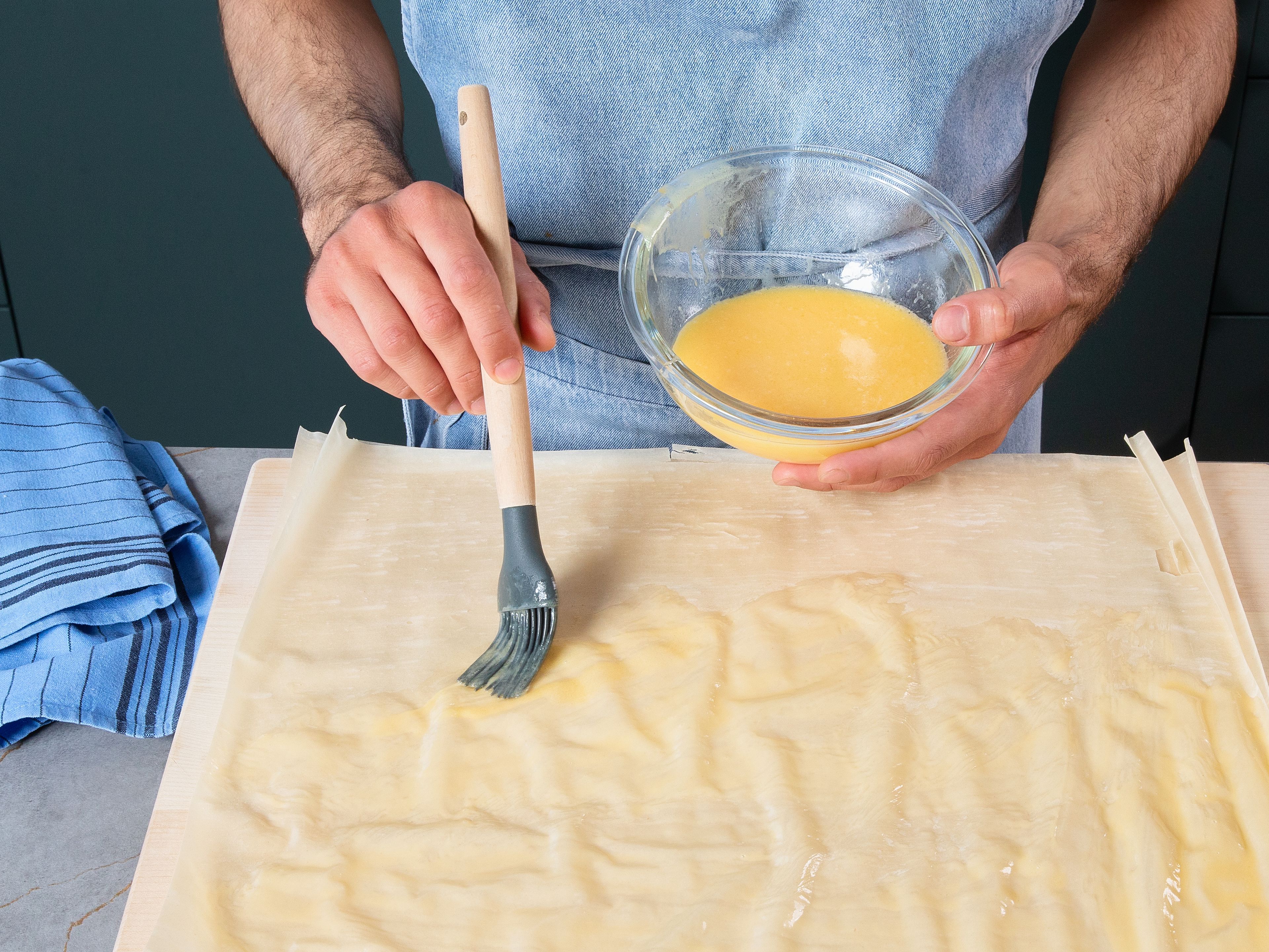 Preheat oven to 180°C/356°F. On a broad surface, spread two yufka dough sheets on top of each other. In a bowl, make the wet mix by whisking egg, milk, and melted butter in a small bowl. Brush all over with the wet mix.