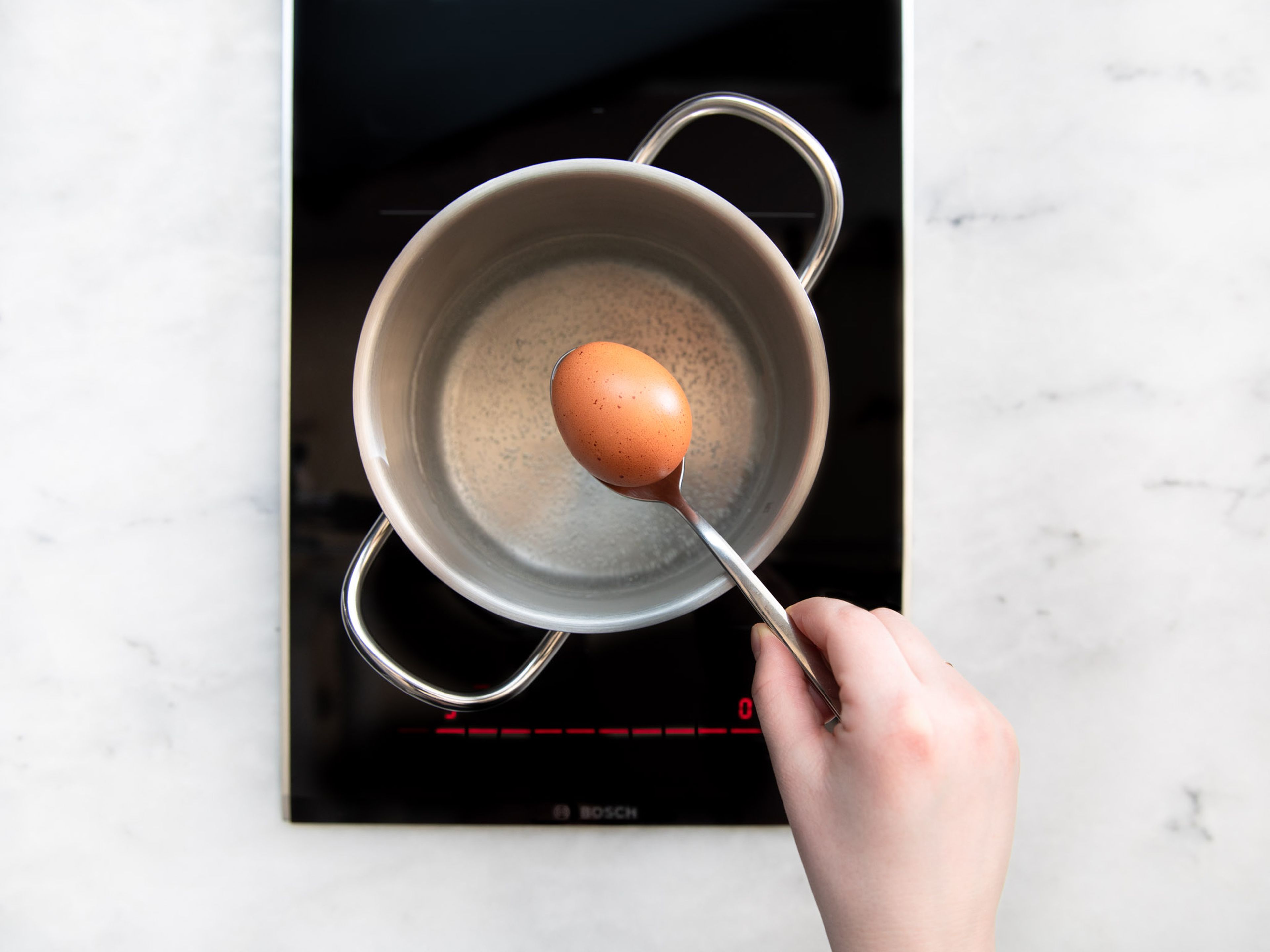 Wasser in einem kleinen Topf zum Kochen bringen. Mit Salz würzen und Eier dazugeben. Für ca. 9 min. kochen lassen, dann Eier mit einem Löffel herausnehmen und in eine Schüssel mit kaltem Wasser geben. Sobald sie kalt genug sind, Eier schälen und halbieren.