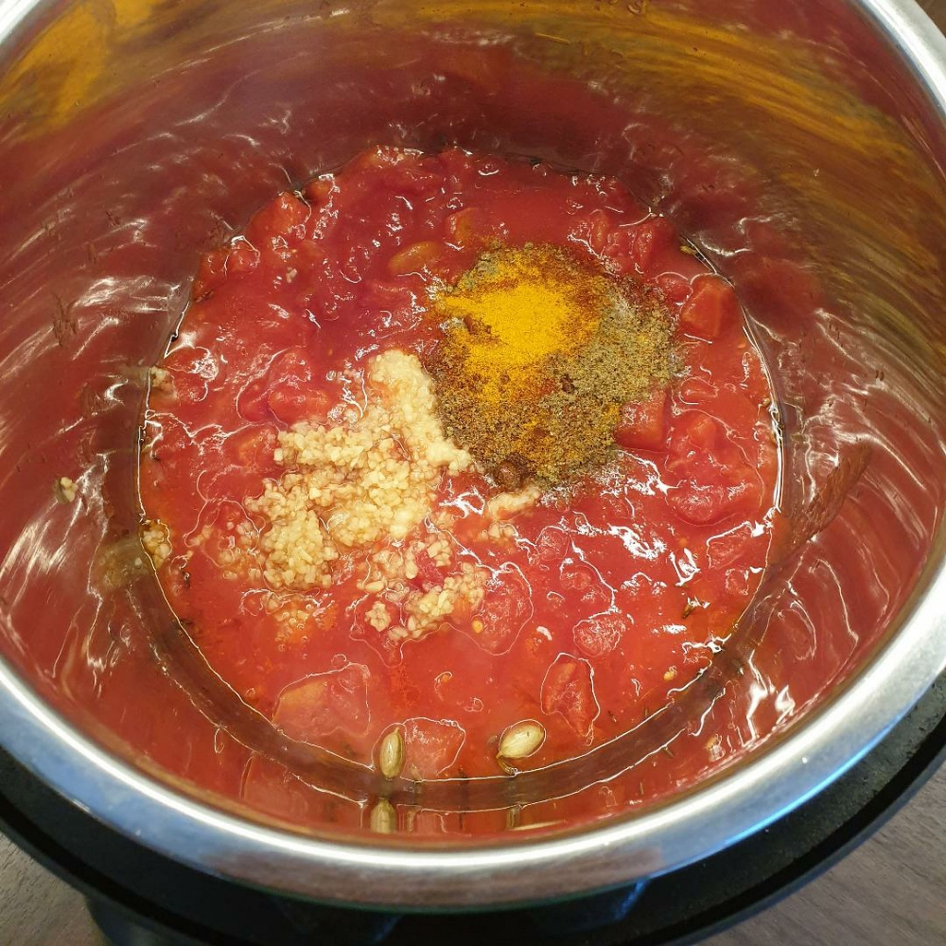 Add the canned tomatoes (including water), garlic, ginger, and dry spices to the Instant Pot and stir.