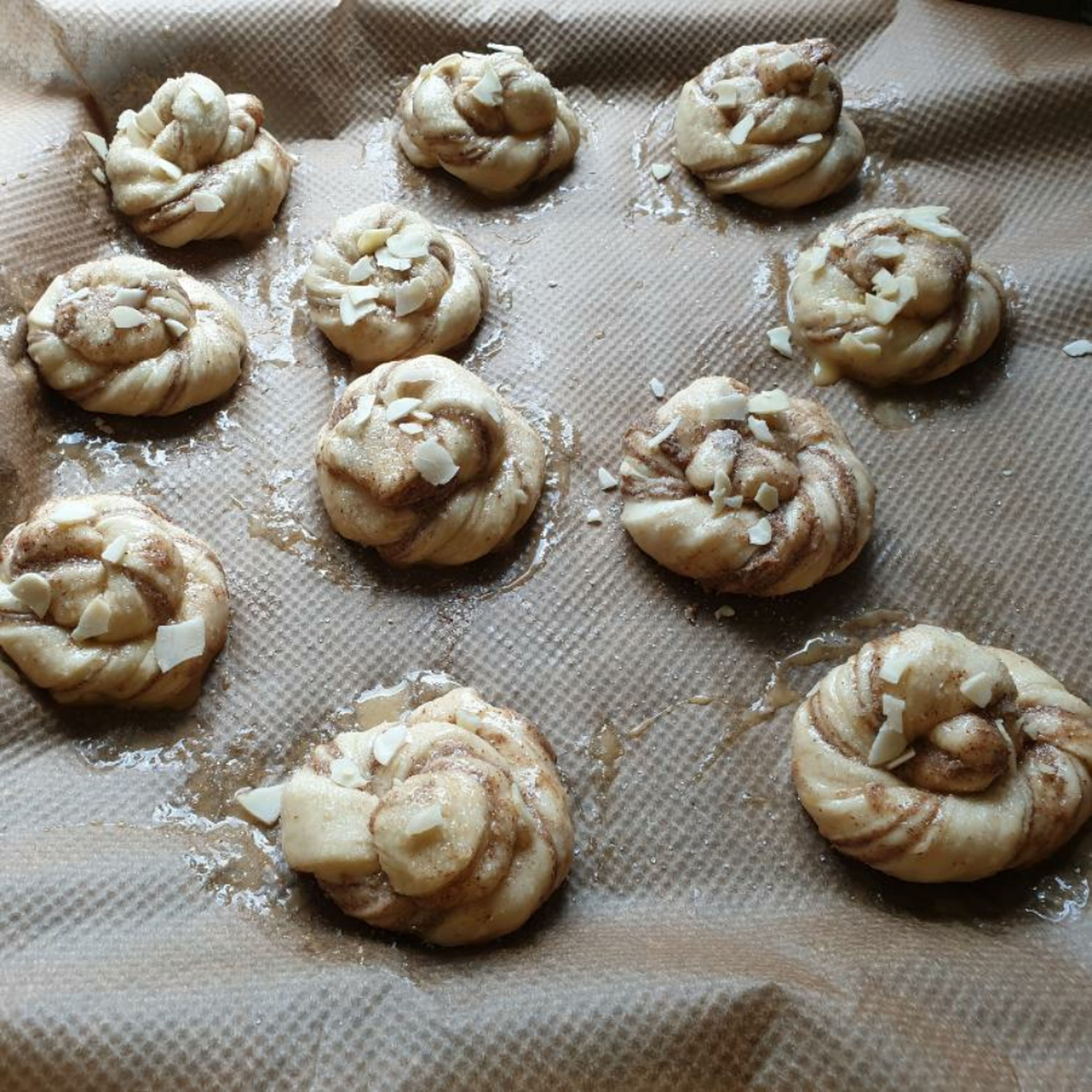 Arrange the shaped dough in a baking tray lined with parchment paper. Brush the buns with egg wash and sprinkle either chopped almonds or pearl sugar.