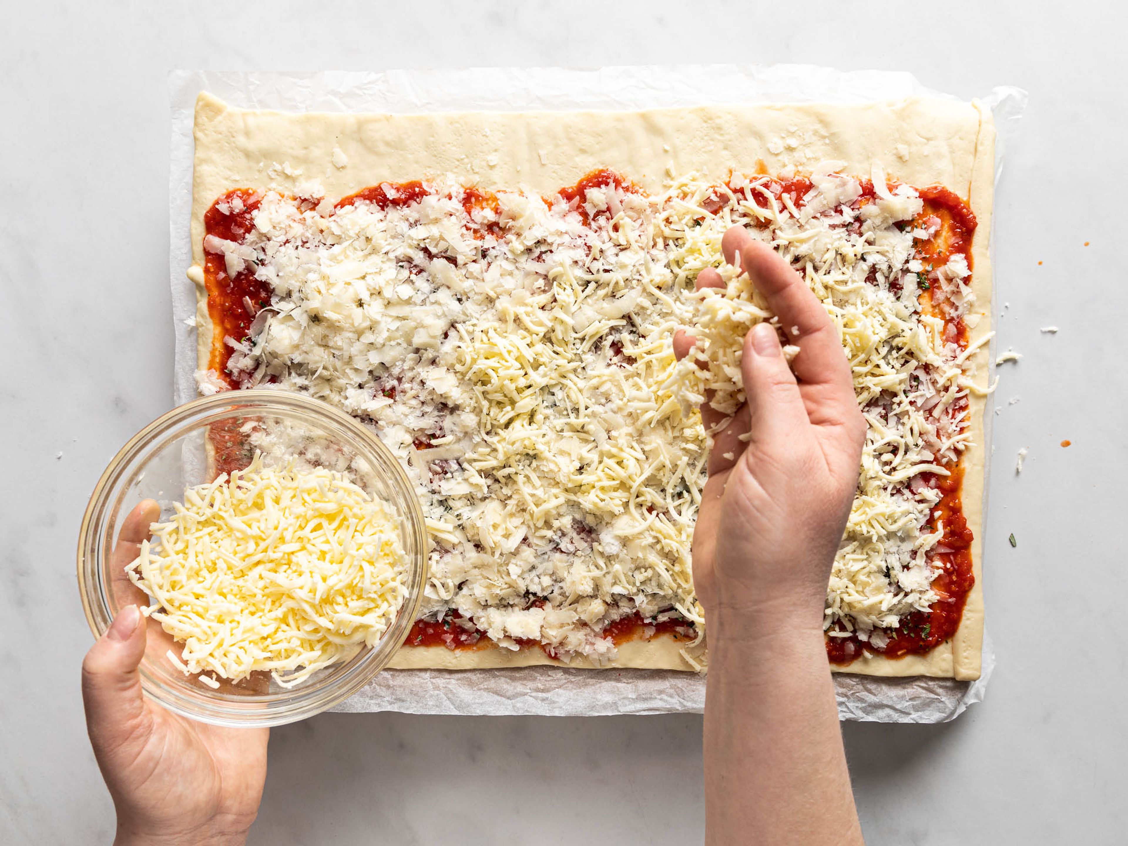 Den Backofen auf 220°C vorheizen. Pizzateig ausrollen und ca. ein Drittel der Sauce auf dem Teig mit einem Löffel verteilen. Die Chiliflocken, Rosmarin und Thymian oder unsere PIZZA PARTY GEWÜRZMISCHUNG (falls verwendet) darüber streuen. Nun den Parmesan und den Mozzarella darauf verteilen. Danach den Teig aufrollen und die Rolle in gleichgroße Scheiben schneiden.