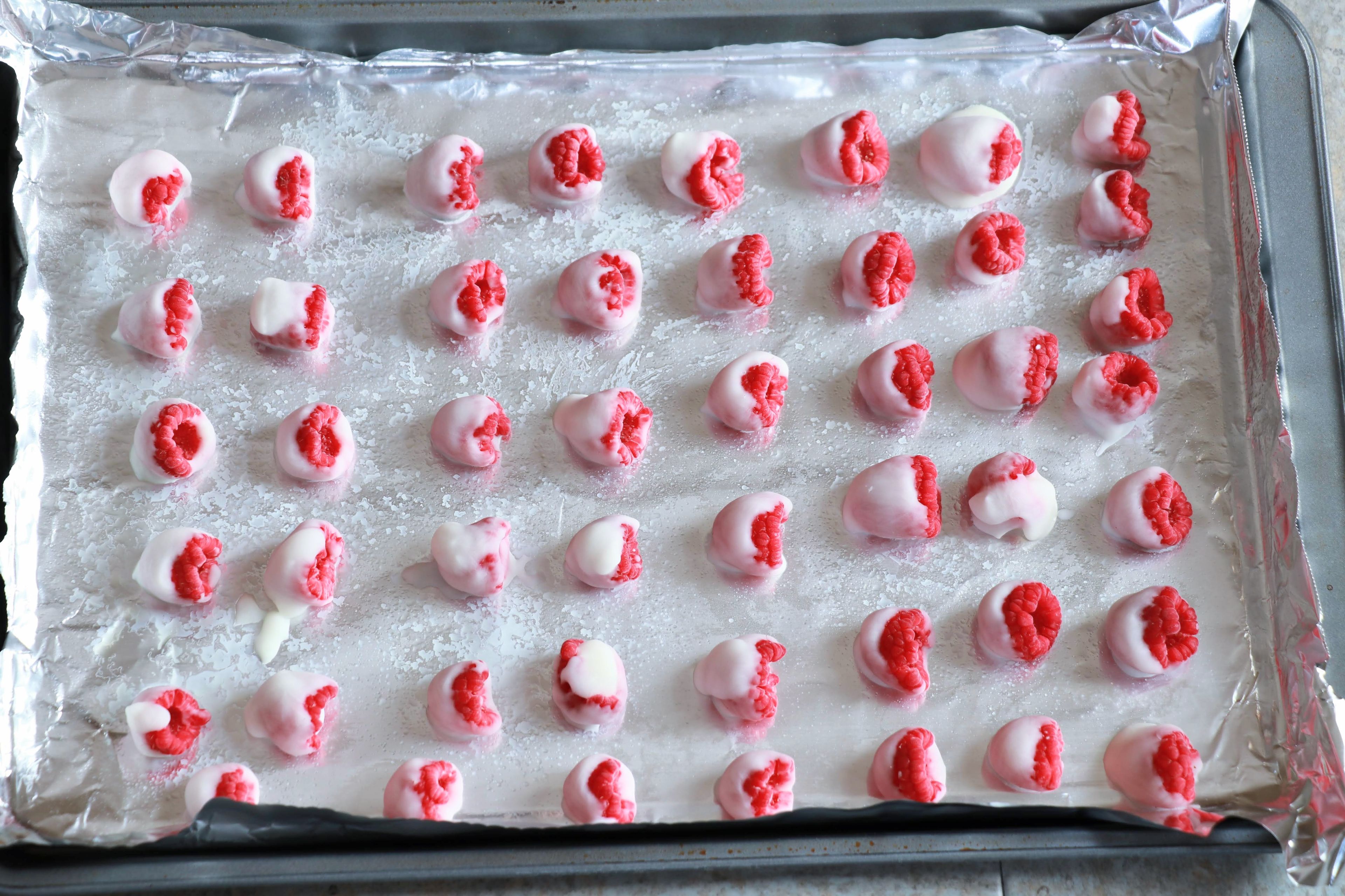 Using a toothpick or your hands, dip the raspberries into the yogurt and place onto a tray.
