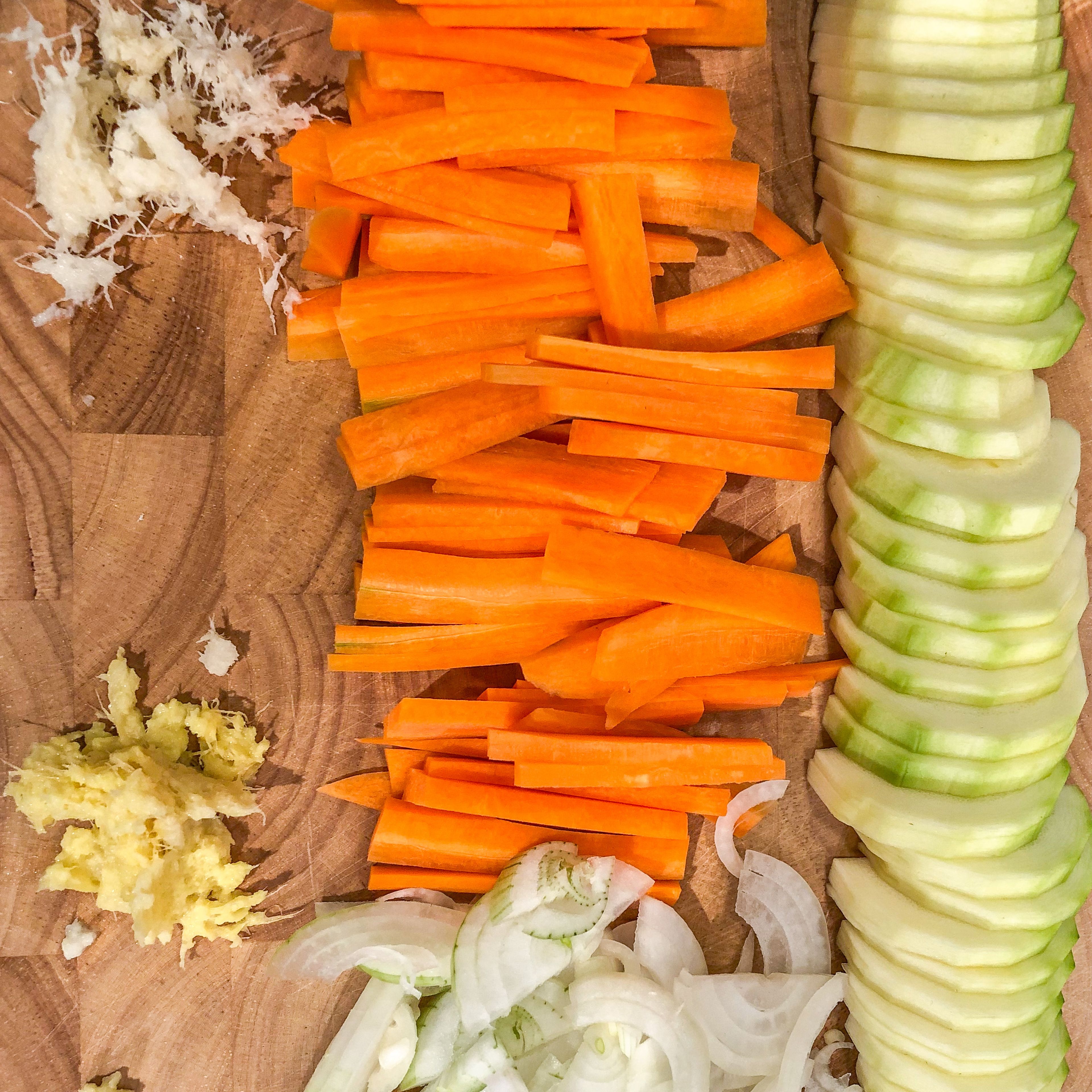 Möhren schälen, in der Länge dritteln und in kleine Stäbchen schneiden. Zwiebeln schälen und in Spalten schneiden. Zucchini schälen, halbieren und in Scheiben schneiden. Ingwer und Galgant schälen und kleinhacken. Die Zwiebelspalten im Wok mit etwas Öl ca. 2 Min. andünsten. Im Anschluss das restliche Gemüse dazugeben und weitere 2 Min. andünsten.