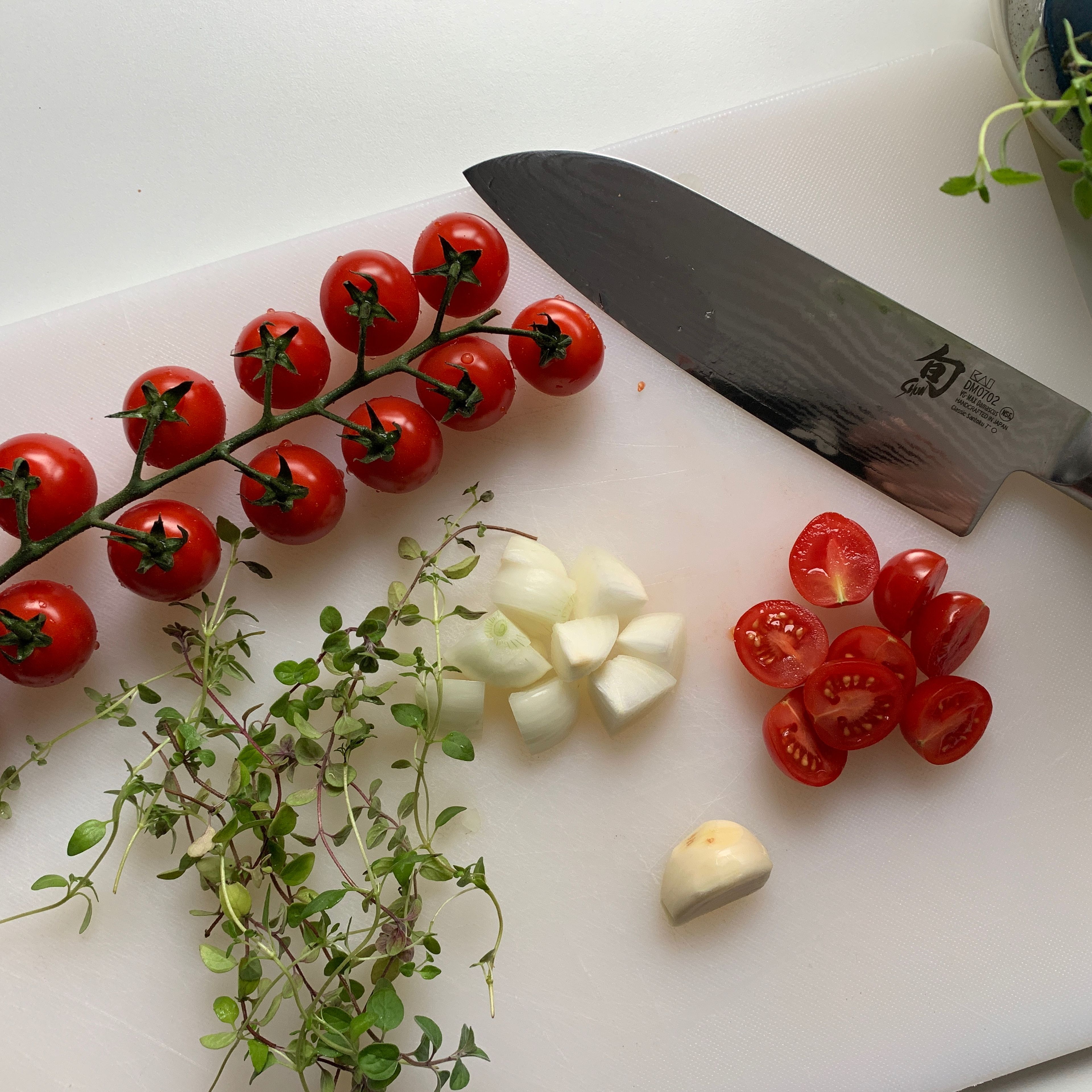 Tomaten halbieren, Zwiebel schälen und grob würfeln, Knoblauch schälen und andrücken, Rosmarin und Thymian zupfen
