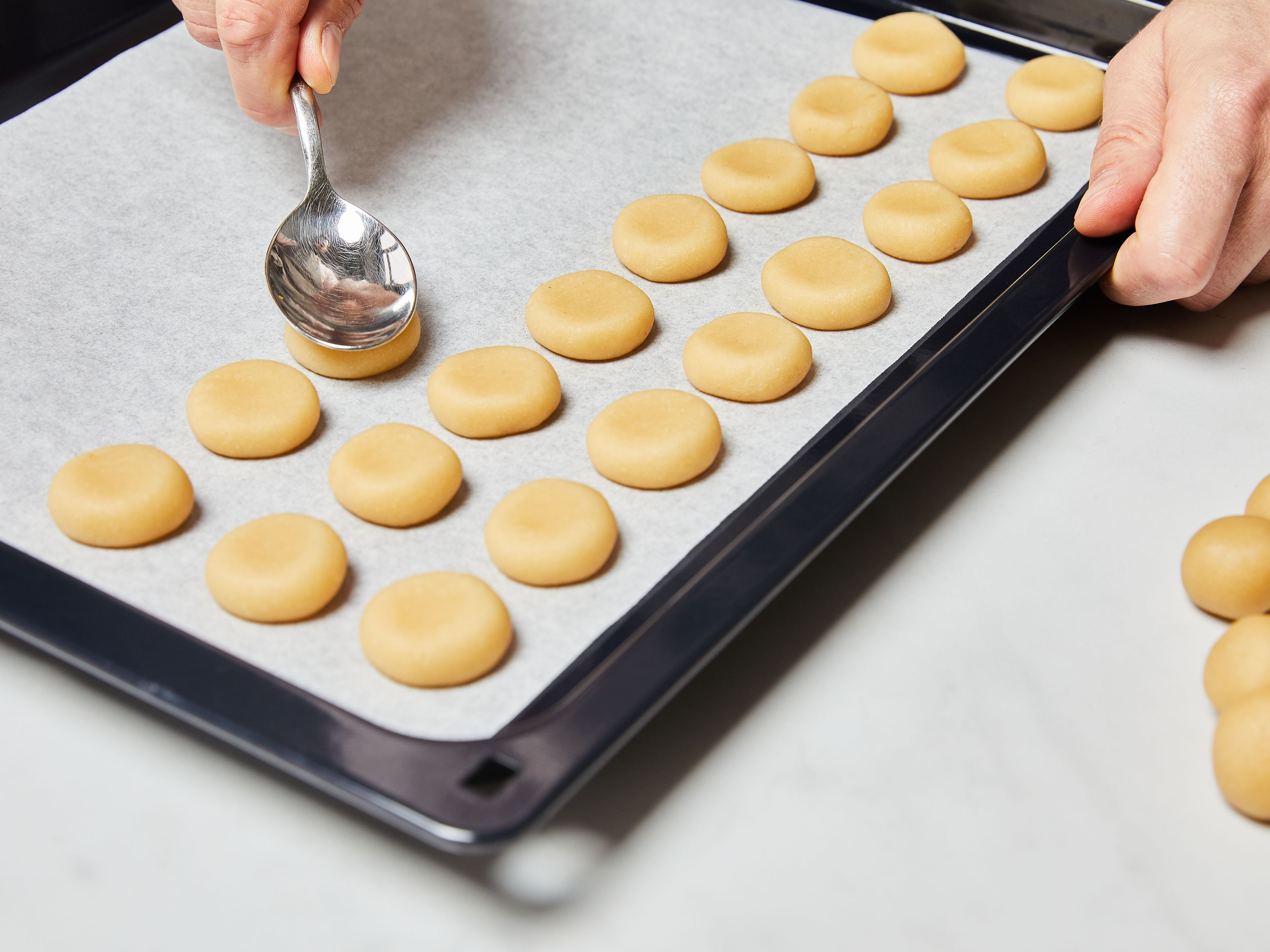With moistened hands, form small balls. Then place them a little apart on a baking sheet lined with parchment paper. Gently flatten each ball of dough with the back of a spoon or your thumb.