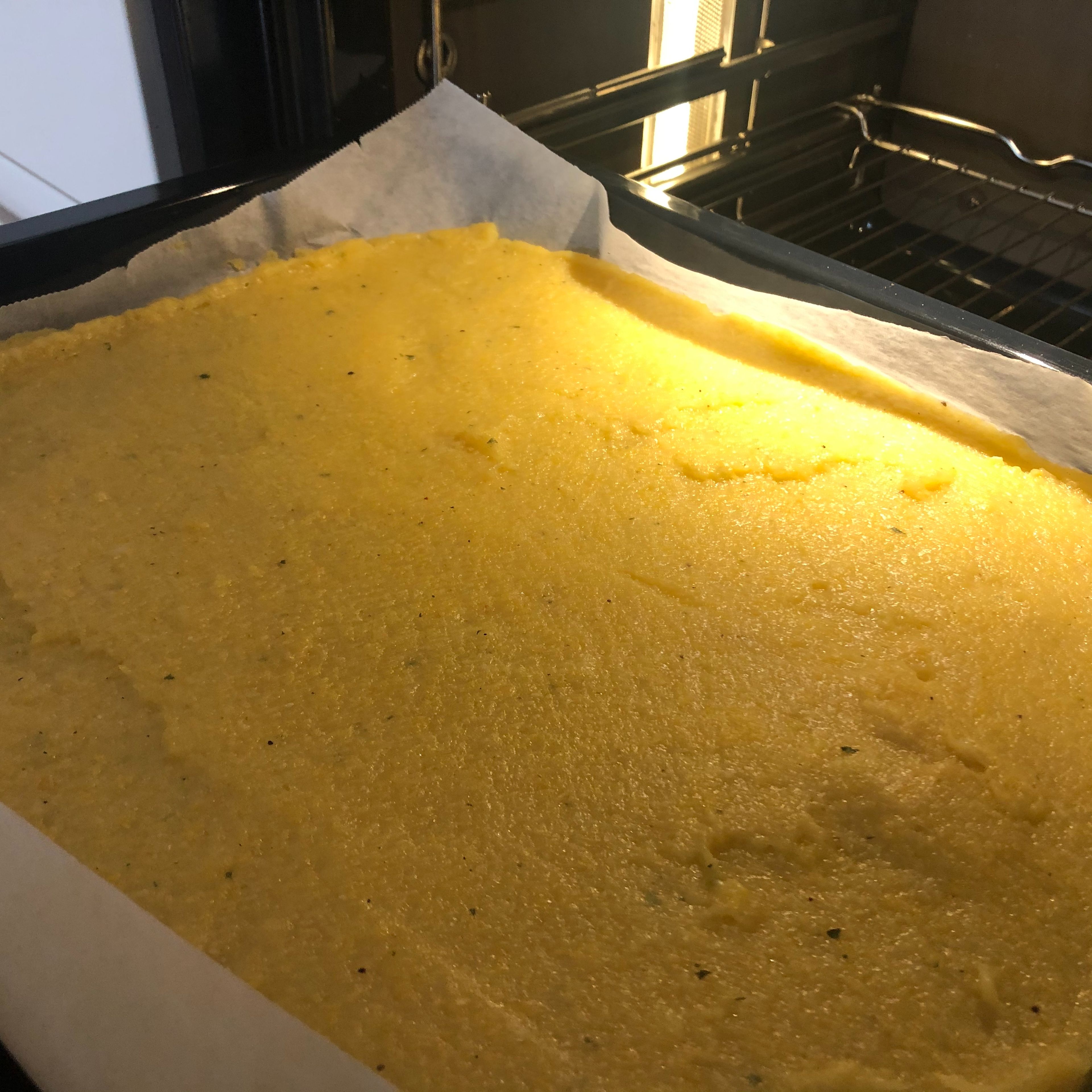 Den Brei auf ein mit Backpapier ausgelegtes Blech 2 cm dick aufstreichen und auskühlen lassen, bis die Polenta fest wird. Anschließend im Backrohr bei ca. 180 Grad für 15min backen.