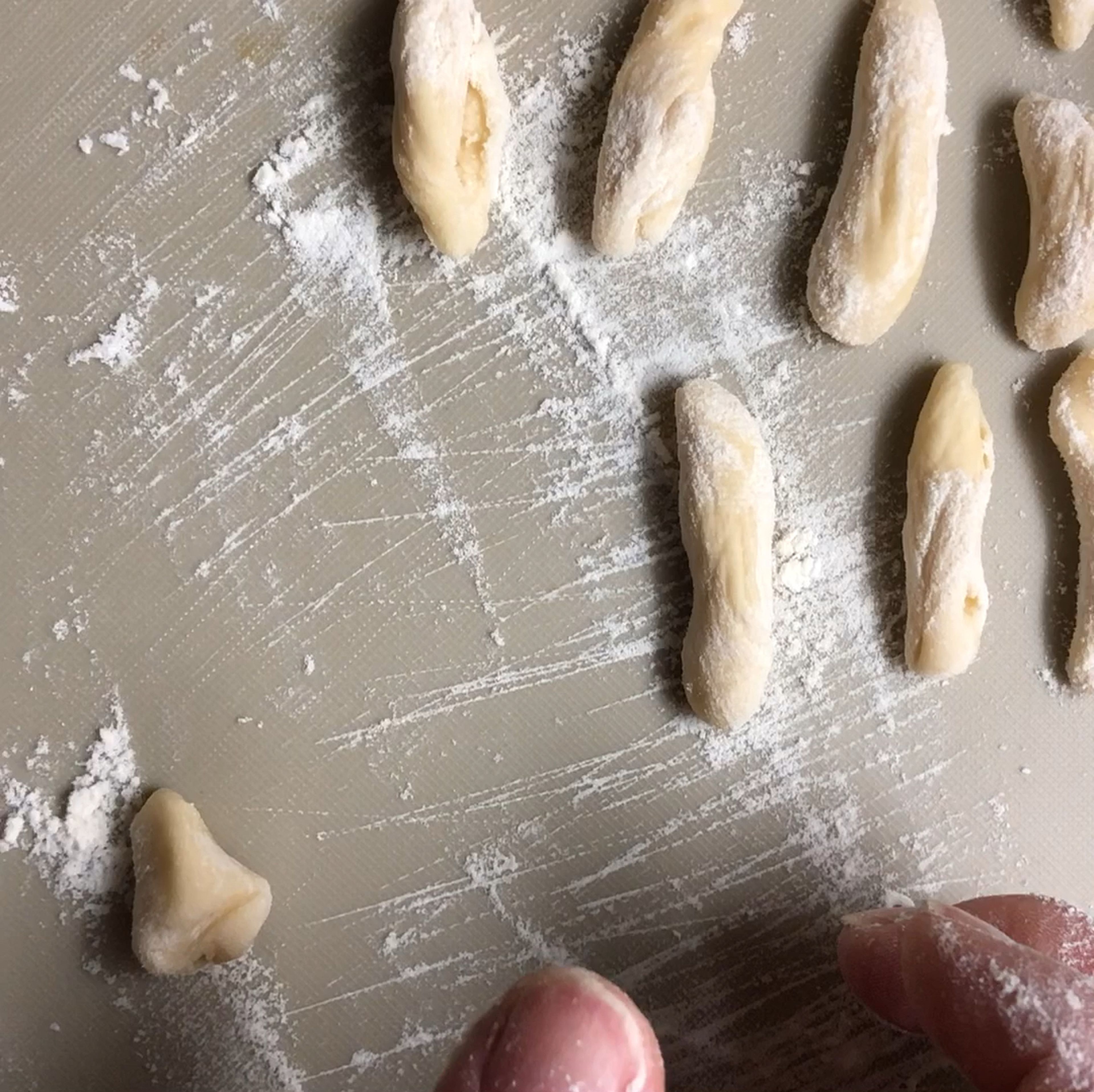 Now the most interesting part begins, as we start to shape our dough into galnash. Take one little dough piece and place your thumb on top of it. Then, press it with your thumb, roll the dough on a flat surface shaping it into a sort of seashell.