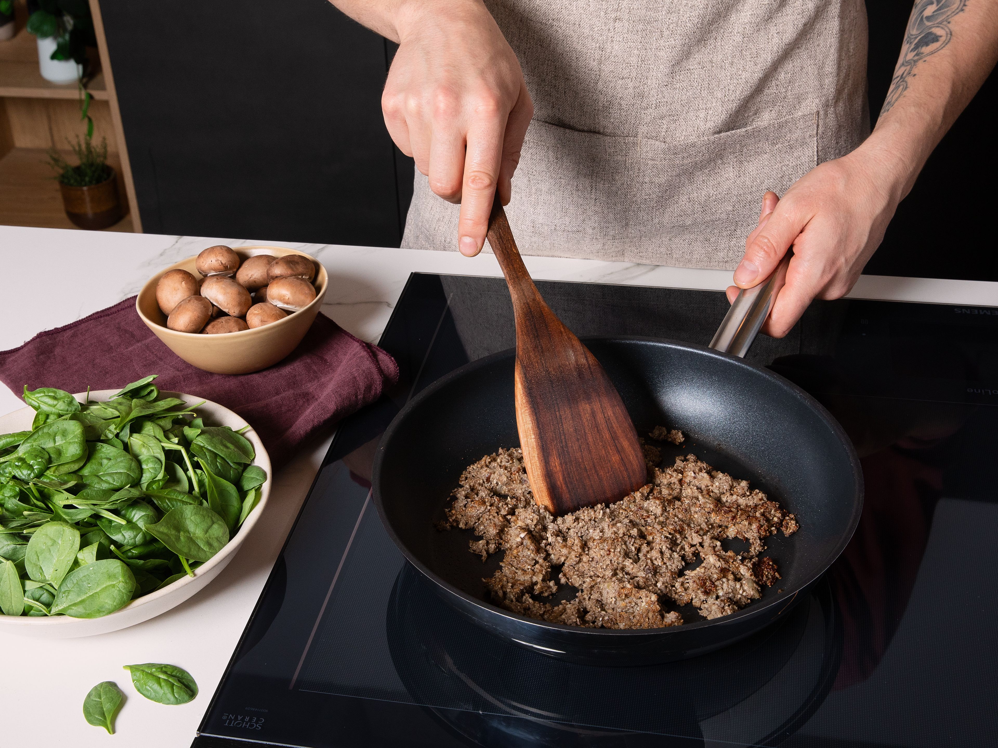 Den Ofen auf 200 °C Ober-/Unterhitze vorheizen. Die Zwiebel und Knoblauch schälen. Pro Portion 1 kleinen Champignon beiseite legen. Die restlichen Champignons putzen und zusammen mit Walnüssen, Zwiebel und Knoblauch in einen Zerkleinerer geben und in feine Würfel zerkleinern. In einer großen Pfanne, Butter erhitzen und die zerkleinerte Füllung bei mittlerer Hitze ca. 8-10 Min. braten, bis die komplette Flüssigkeit verdampft ist.