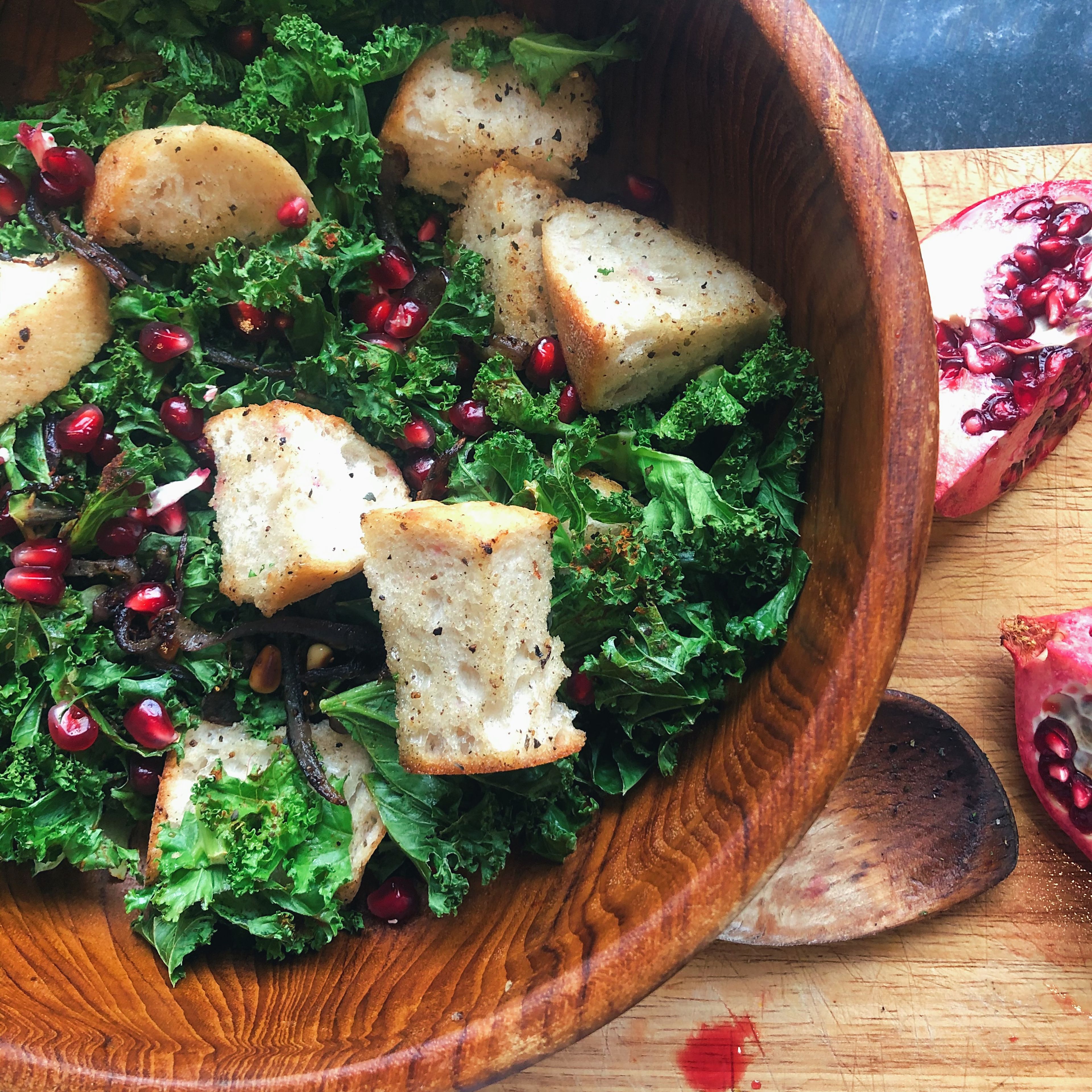 Add kale and bread mix to a bowl and sprinkle pomegranate seeds over the top.