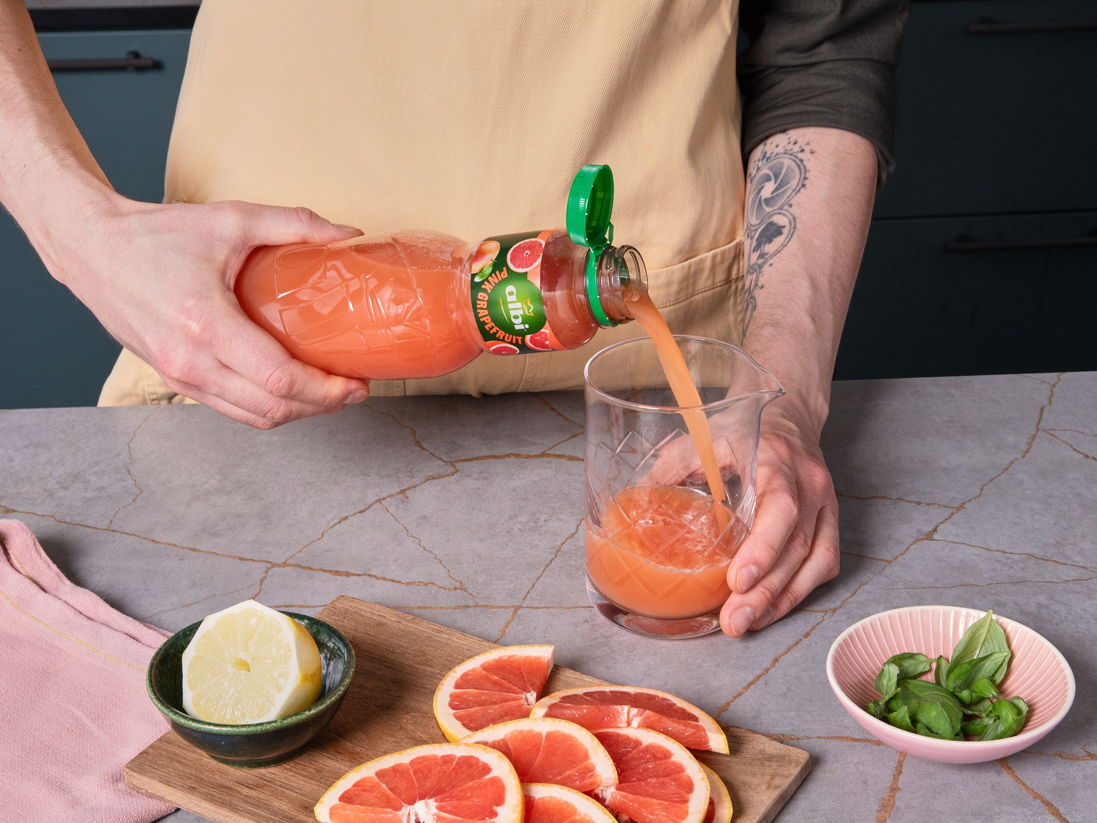Zitrone auspressen. Grapefruit als Dekoration in dünne Halbmonde schneiden. Den ausgepressten Zitronensaft zusammen mit albi Pink Grapefruitsaft und der abgeseihten Basilikum-Infusion in ein großes Rührgefäß geben und gut verrühren.