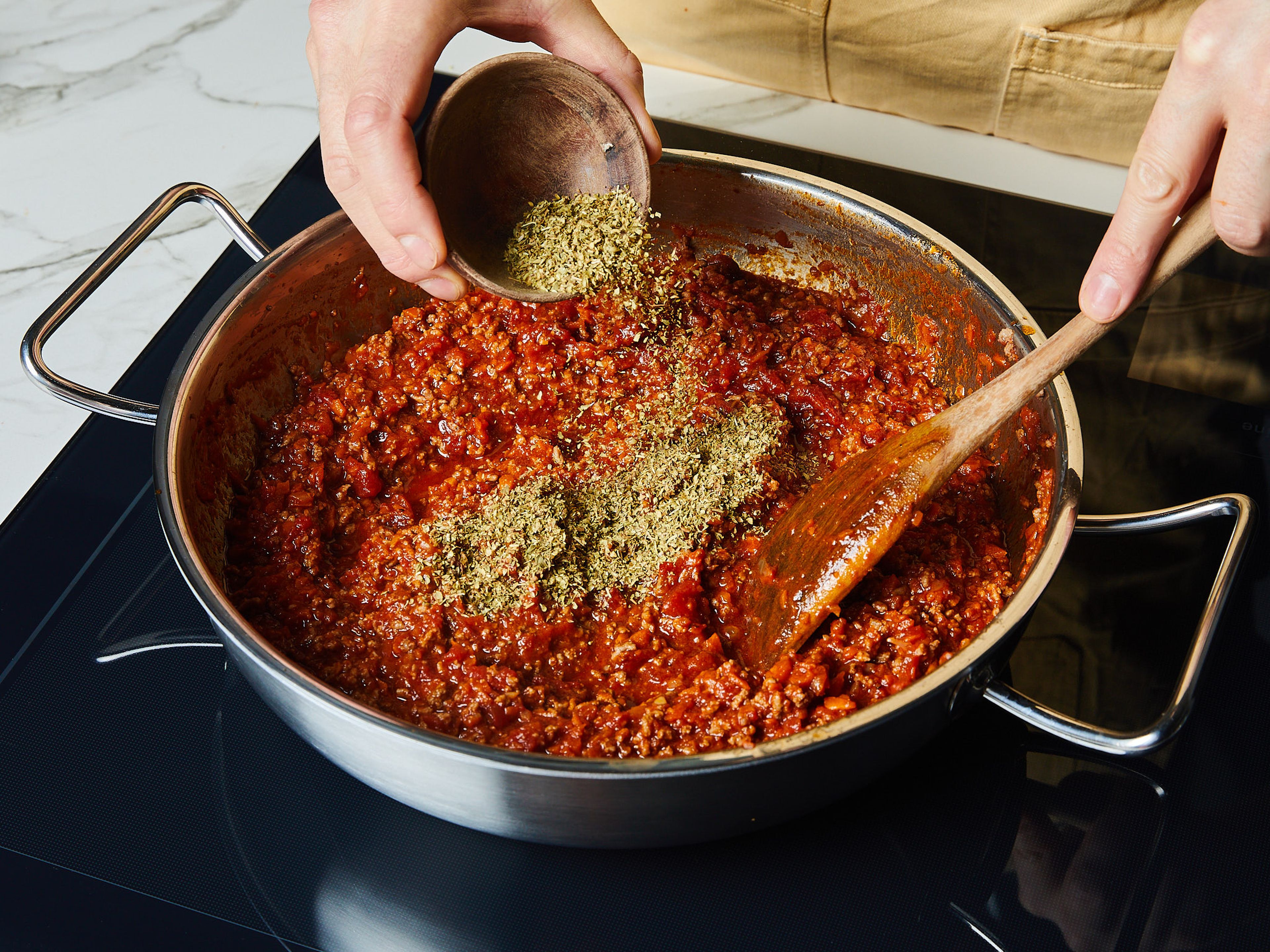 Für das Lasagne Rezept den Knoblauch schälen und fein hacken. Zwiebel und Karotten schälen und würfeln. Etwas Olivenöl in einer großen Pfanne erhitzen und die Zwiebeln, Karotten und den Knoblauch darin anbraten. Das Rinderhackfleisch hinzugeben, gleichmäßig anbraten und dabei mit einem Holzlöffel zerkleinern. Mit Salz und Pfeffer abschmecken. Dann die gehackten Tomaten hinzufügen und erneut mit Salz und Pfeffer würzen. Zugedeckt bei mittlerer Hitze ca. 15-20 Min. köcheln lassen. Dann den getrockneten Oregano einrühren.