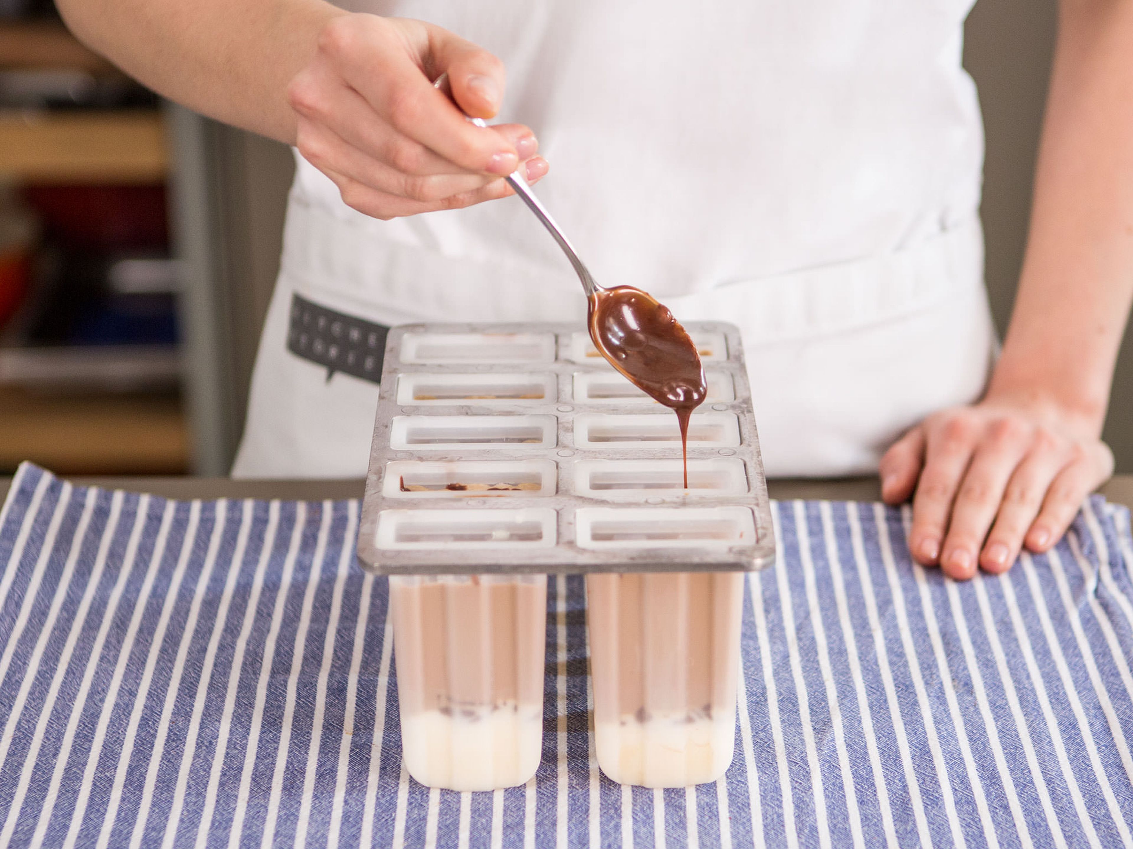 Roughly chop chocolate. Heat remainder of cream in a small saucepan over low heat, add chocolate, and stir until melted. Now, add chocolate to each popsicle mold. Close your popsicle mold and insert popsicle sticks. Place in freezer for approx. 4 – 6 h.