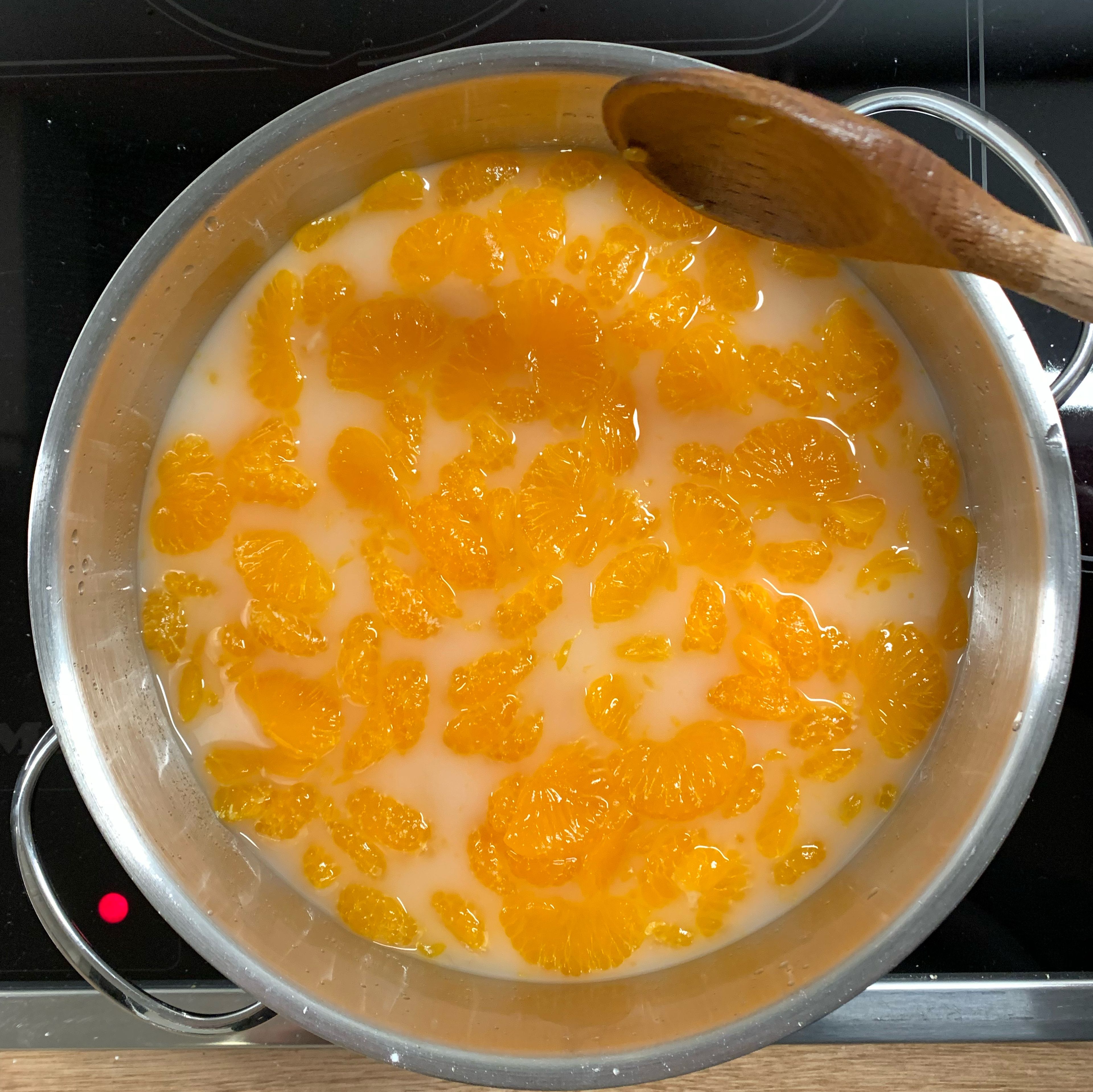 Mandarinen dem Saft zugeben und aufkochen. Vorsichtig mit einem Kochlöffel rühren, so dass die Mandarinen ganz bleiben.