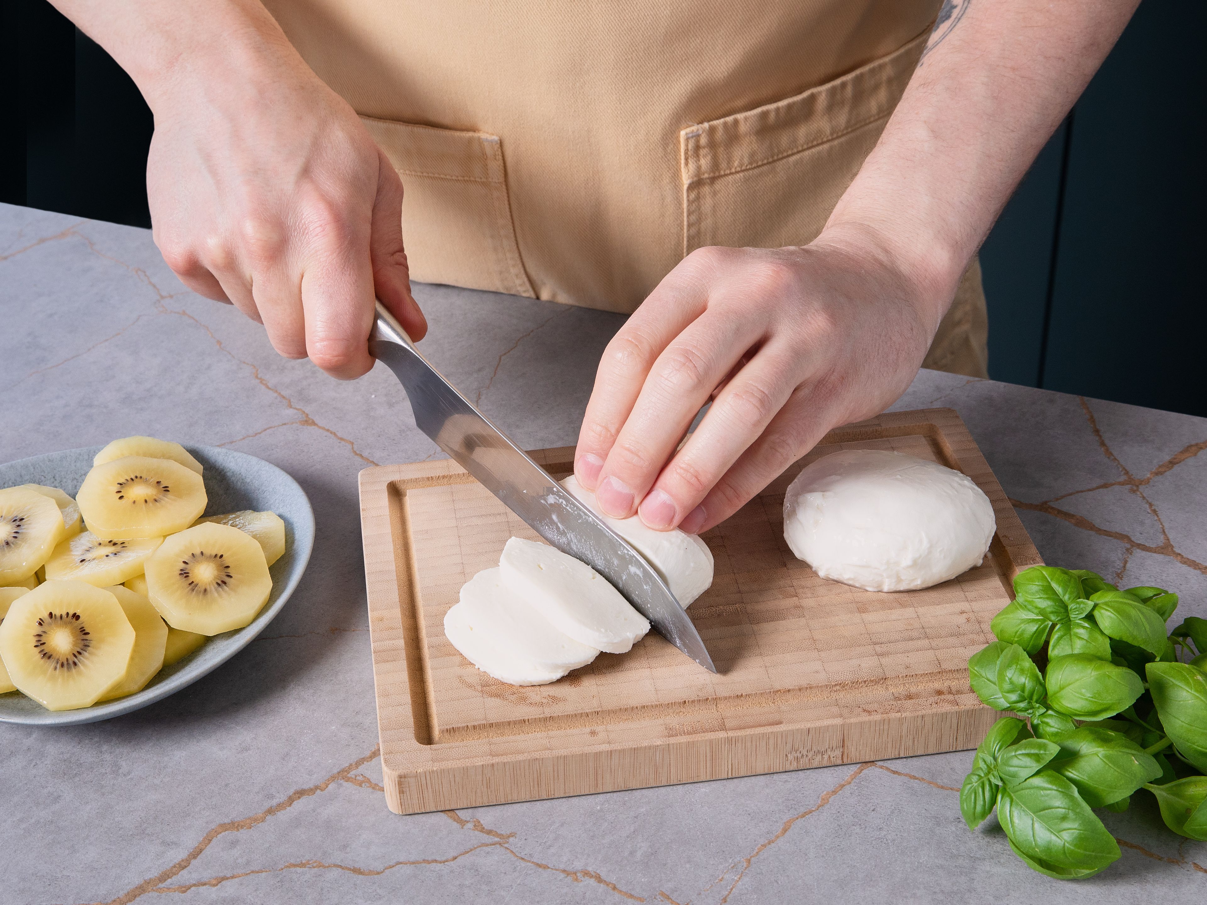 Mozzarella gut abtropfen lassen, trocken tupfen und in Scheiben schneiden. Basilikum waschen, trocken schütteln und die Blätter abzupfen.