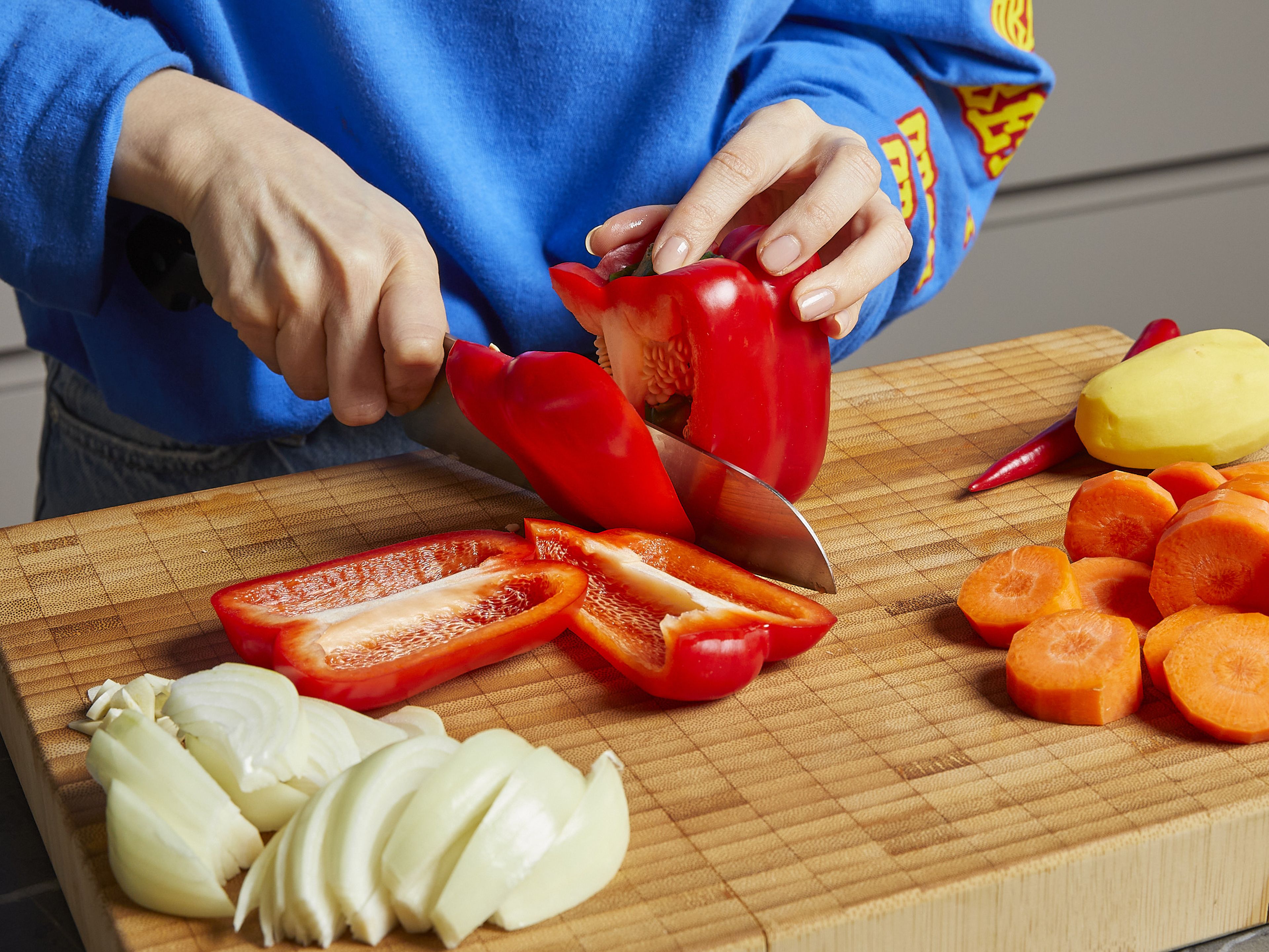 Peel the potato, carrot, onion, and garlic. Then, dice the potato, carrot, red bell pepper, and onion into bite sized pieces. Finely chop or cut the garlic and chili into thin rings.