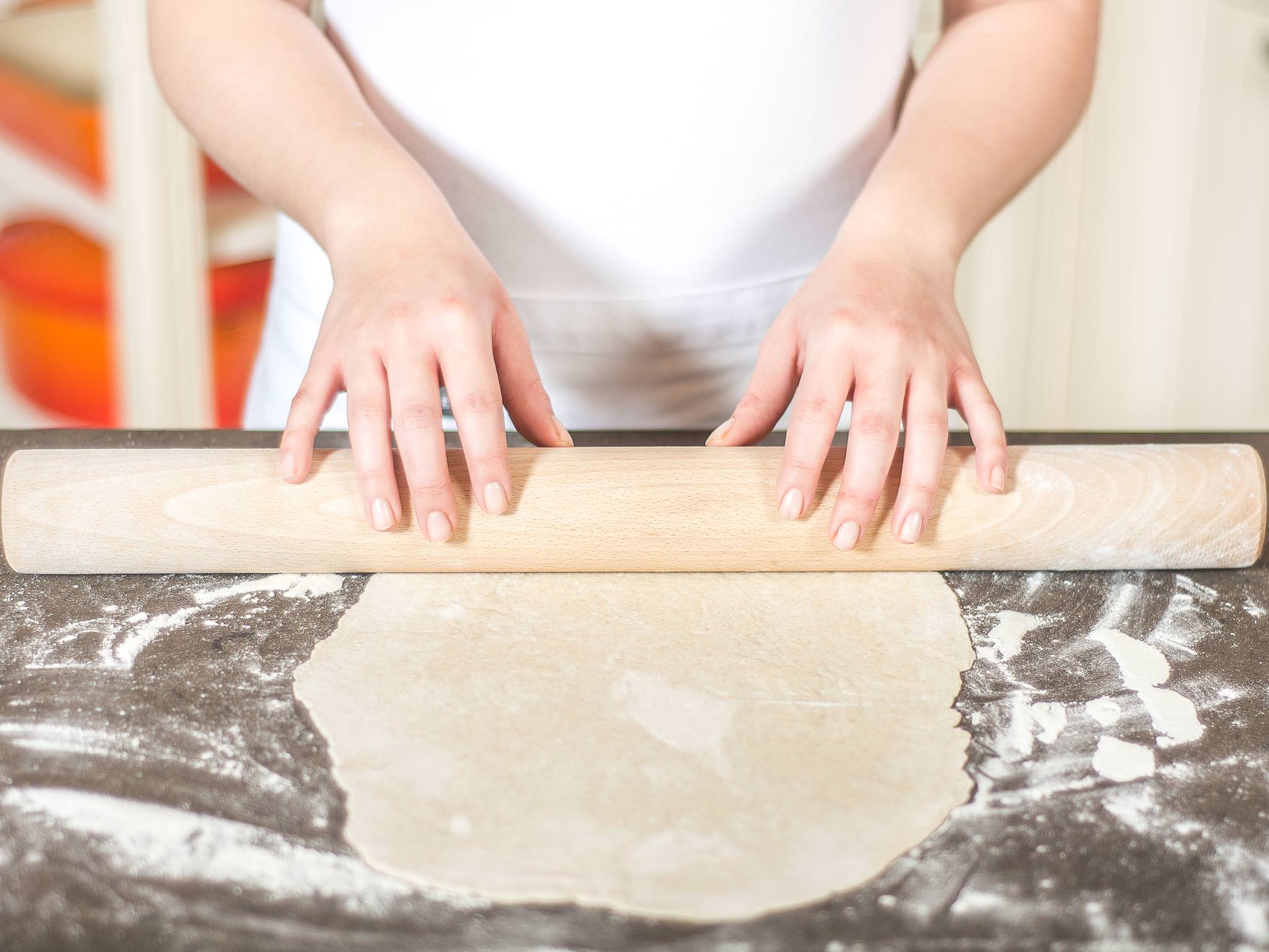 Separate dough into two halves and roll each one out as thinly as possible on a work surface sprinkled with flour.