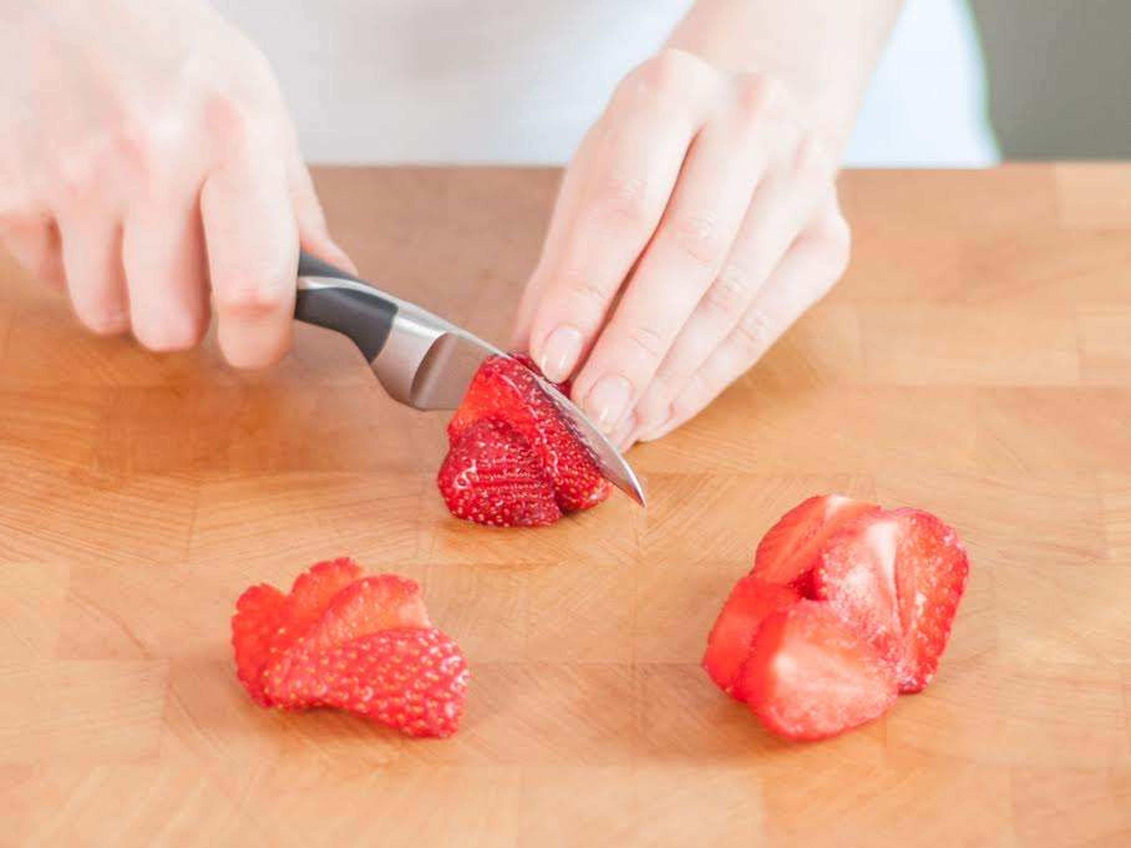 Backofen auf 190°C vorheizen. Backblech mit Backpapier auslegen. Strunk der Erdbeeren entfernen. Einen Teil der Erdbeeren halbieren und in eine große Schüssel geben. Restliche Erdbeeren zum Servieren in Scheiben schneiden und beiseitestellen.