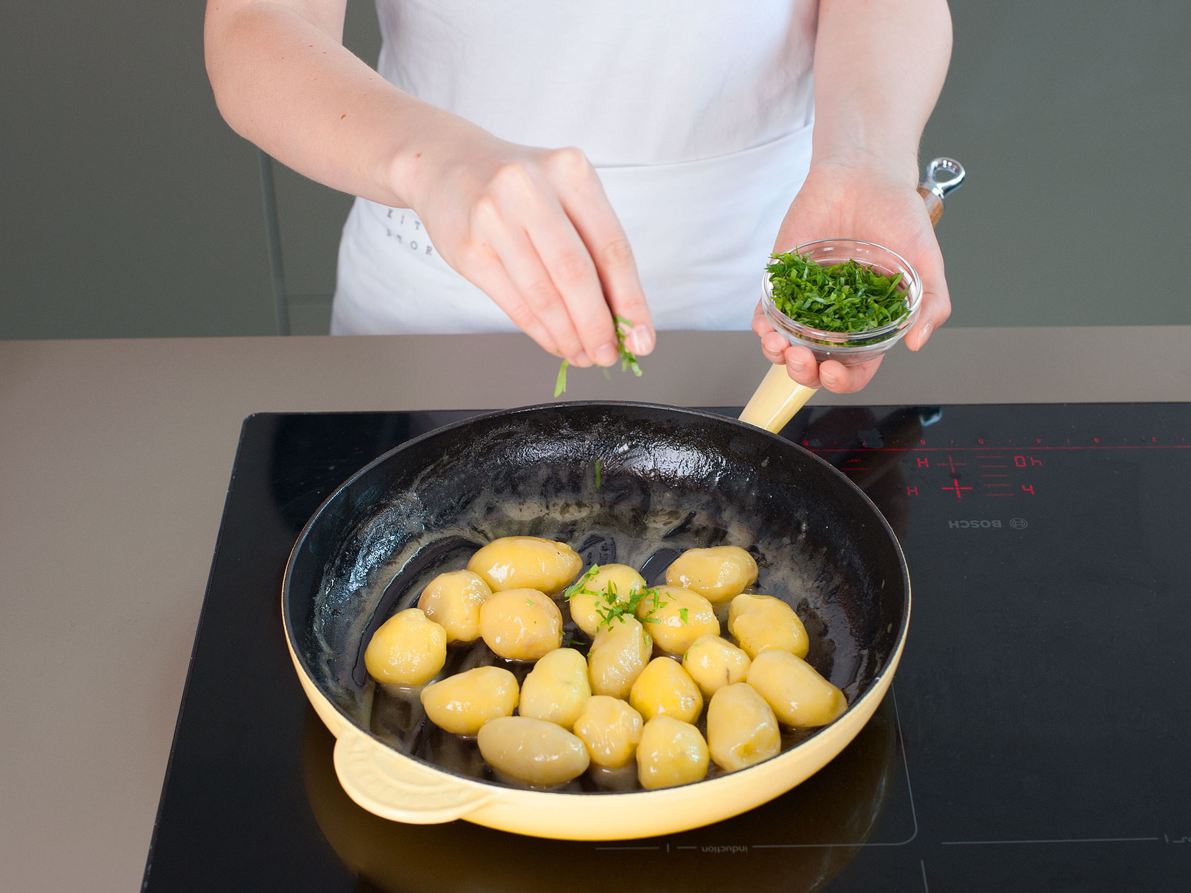 In a large saucepan, cook potatoes in salted water over medium heat, approx. 10 - 15 min. Drain and peel potatoes, then return to pan and sauté in half the butter and some veal stock,  approx. 3 - 5 min. Remove from heat, cover, and set aside. Add freshly chopped parsley right before serving.