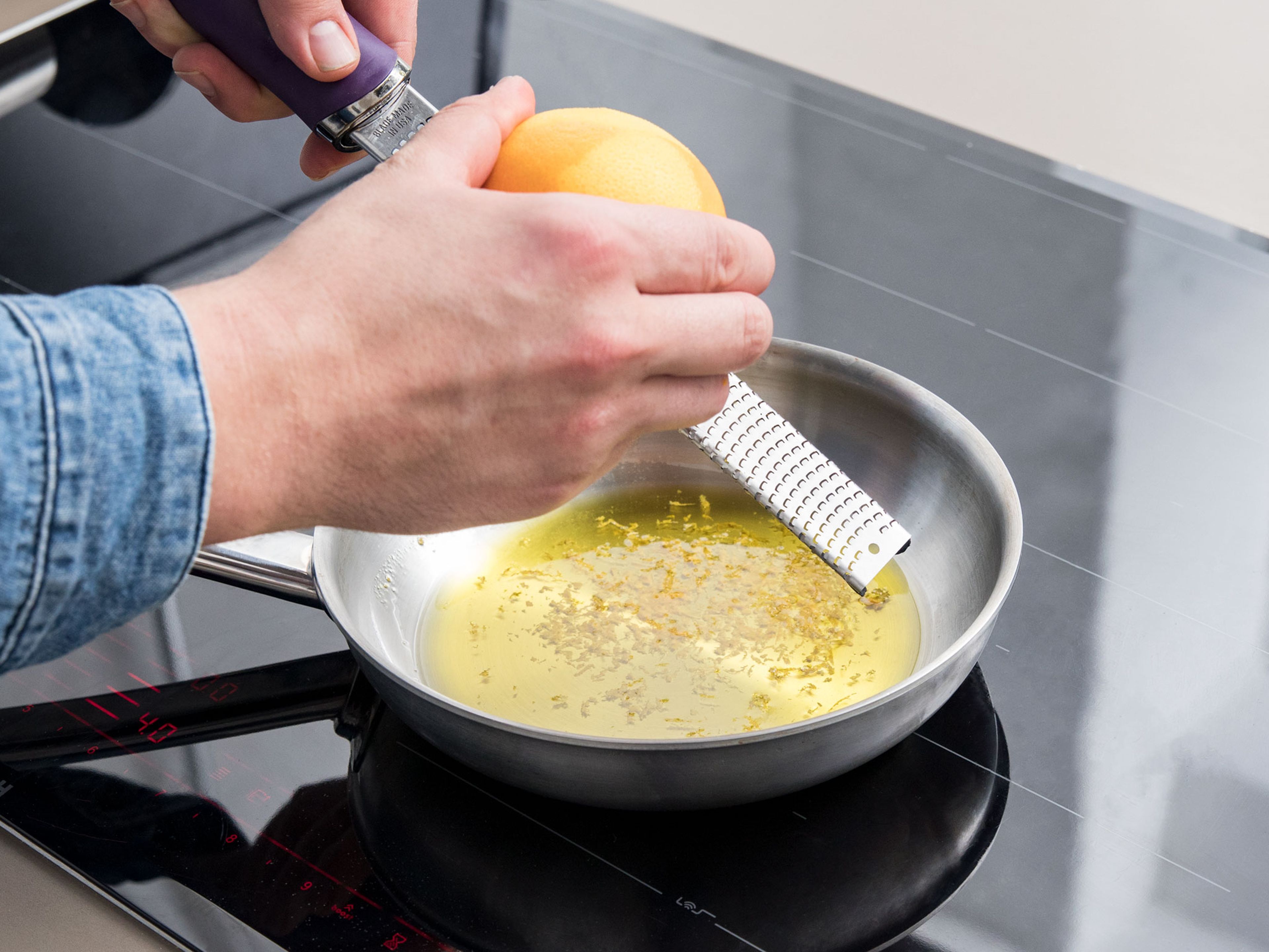Backofen auf 230°C vorheizen. Olivenöl in einer kleinen Pfanne erhitzen und Orangenschale hinein reiben. Etwas köcheln lassen, damit die Orangenschale ihr Aroma an das Olivenöl abgeben kann.