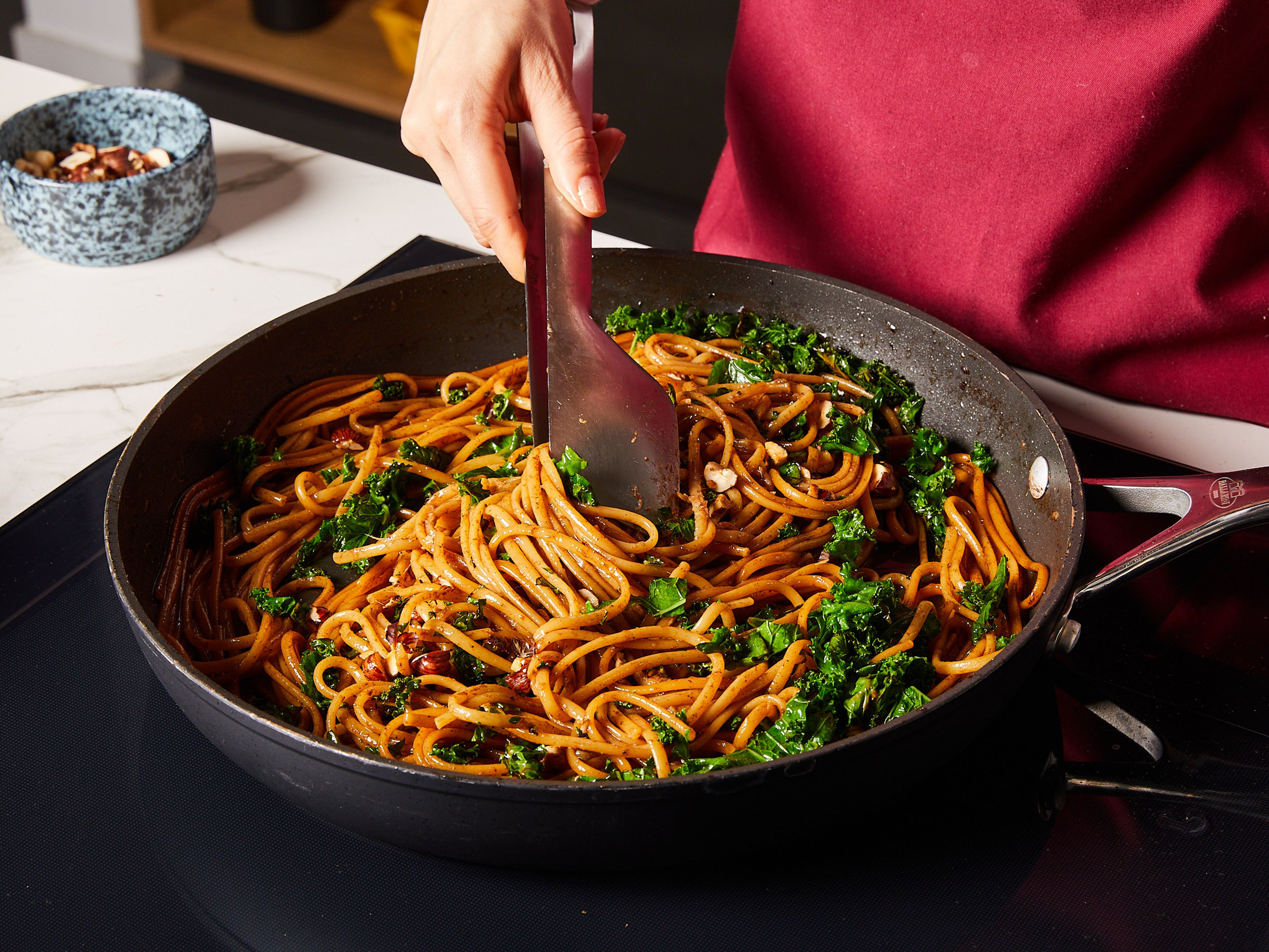 Add cooked linguine to the pan and toss well with the sauce. Then, stir in half of the freshly grated Pecorina until it melts and the pasta becomes creamy. If desired, add more pasta water. Mix in half of crispy kale and toasted hazelnuts. Season with salt, pepper, and optionally chili flakes. Divide into plates and top with remaining kale, hazelnuts, Pecorino, and a bit of lemon zest.