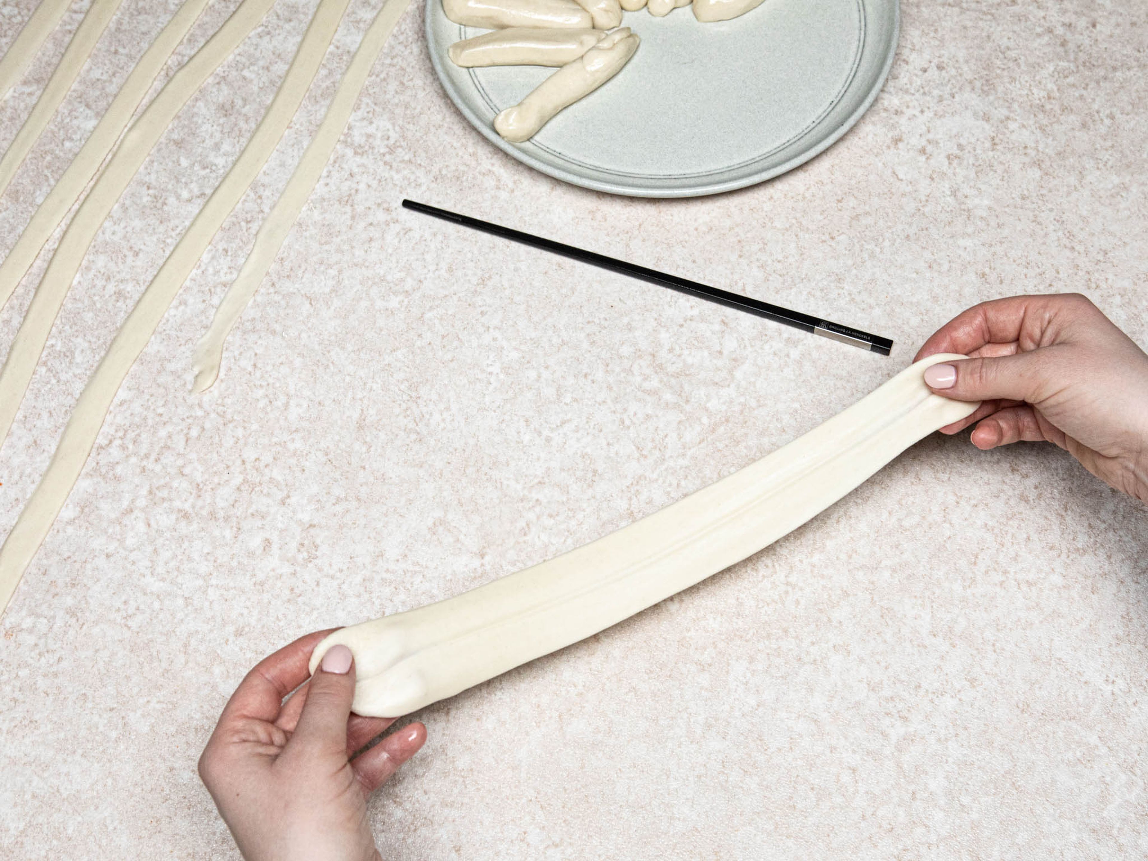 Gently tug on each end of the rectangles to slightly stretch it, then lightly hit it against the working surface. Separate the noodles where the chopstick was pressed into.
